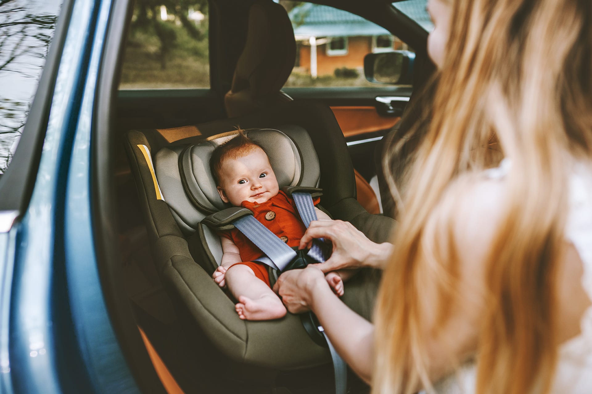 Urlaub mit Baby | Baby wird im Autokindersitz von Mama angeschnallt