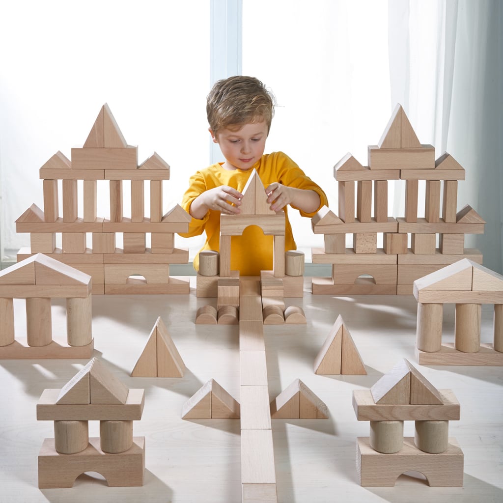 Fröbel Kindergarten | kleiner Jung baut mit Holzbausteinen, Schlösser und Häuser mit Säulen, Recht- und Dreieck