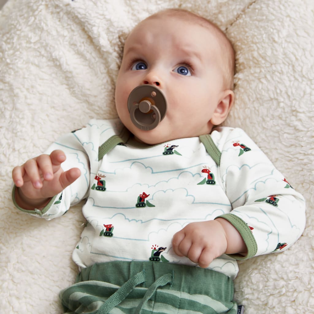 Schnuller abgewöhnen |  Image | Baby liegt auf Kissen und hat einen braunen Schnuller im Mund