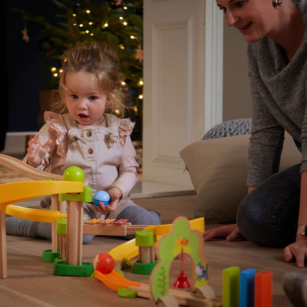 Exklusive Geschenketipps von HABA für das Weihnachtsfest | Mutter und Tochter spielen gemeinsam mit Kullerbü. Leuchtender Tannenbaum im Bildhintergrund
