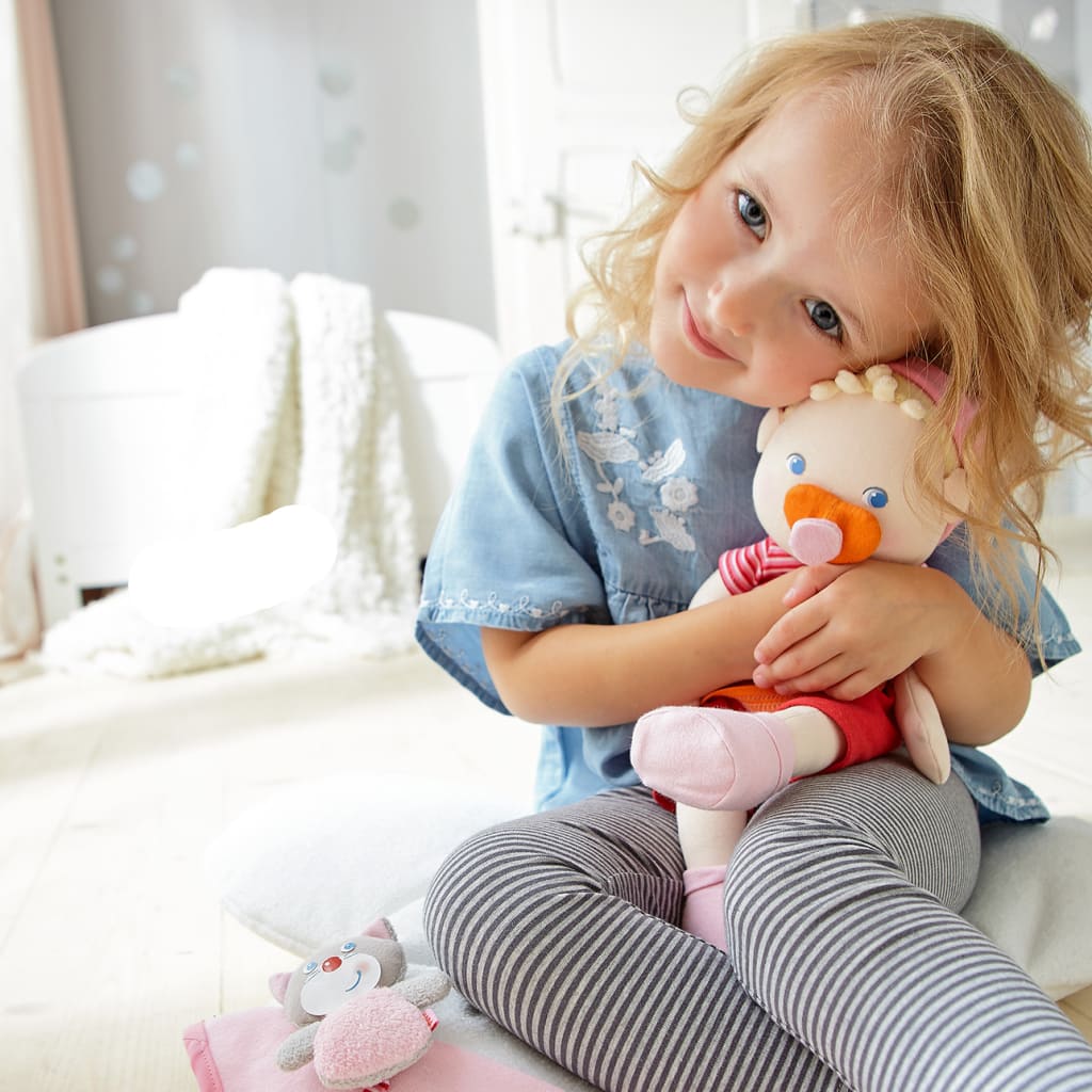 Entspannter Besuch beim Kinderarzt | kleines blondes Mädchen kuschelt mit ihrer Puppe