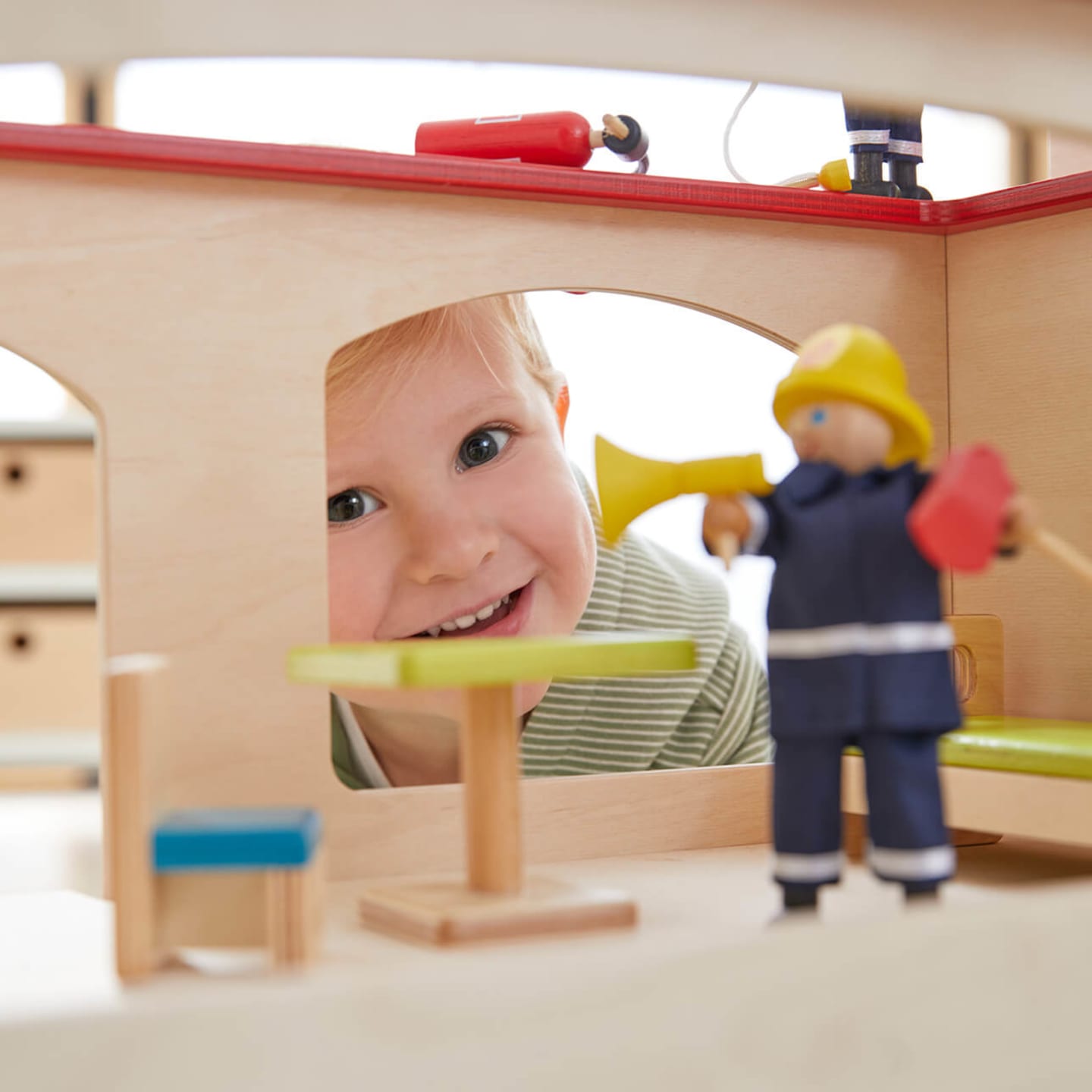 Kliniken | 2 | Image | Kind schaut in Puppenhaus mit Playmobil Feuerwehrfigur