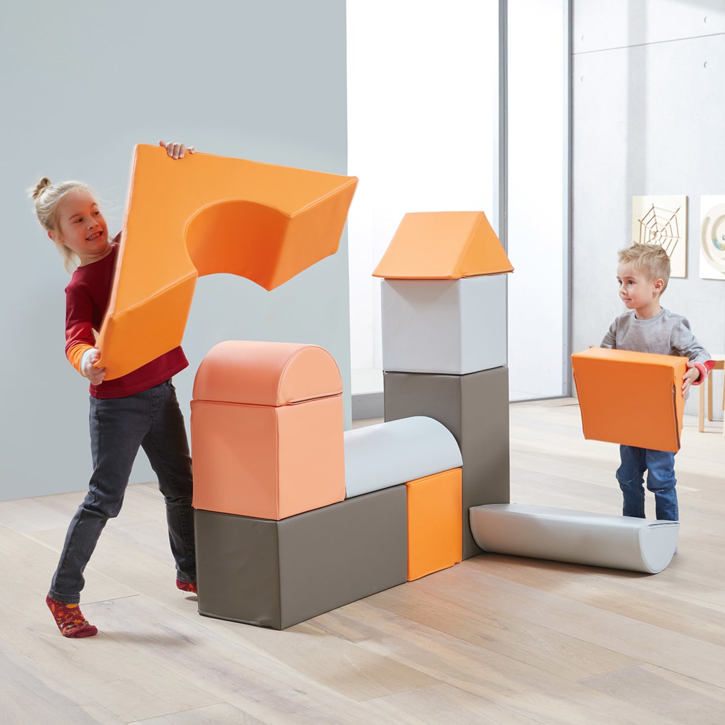 Indoor-Spielplatz | 4 | Bausteine-Set | Kinder spielen mit großen Bausteinen in Orange und grau