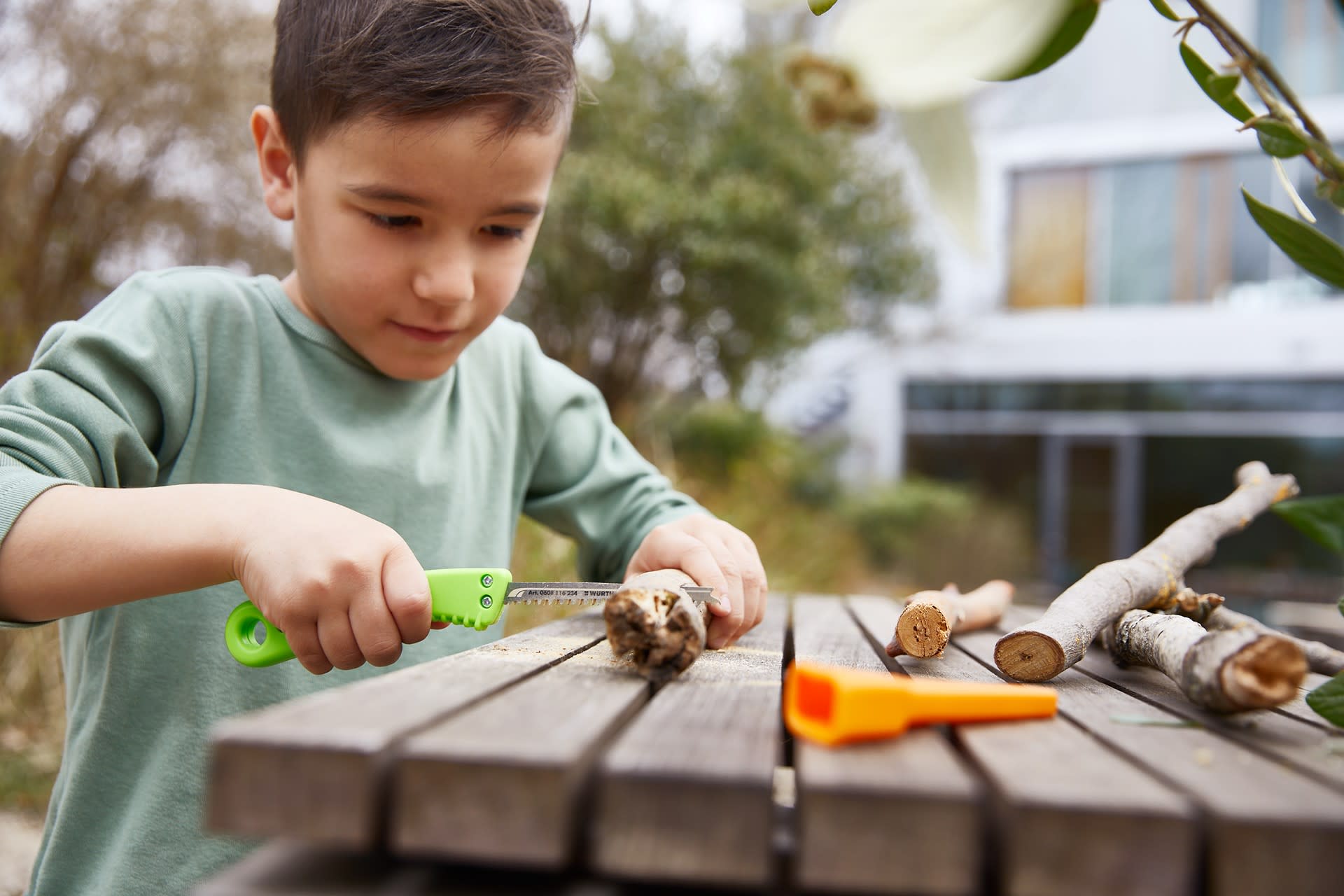 Basteln mit Kindern | Junge sägt an Ast, am Tisch