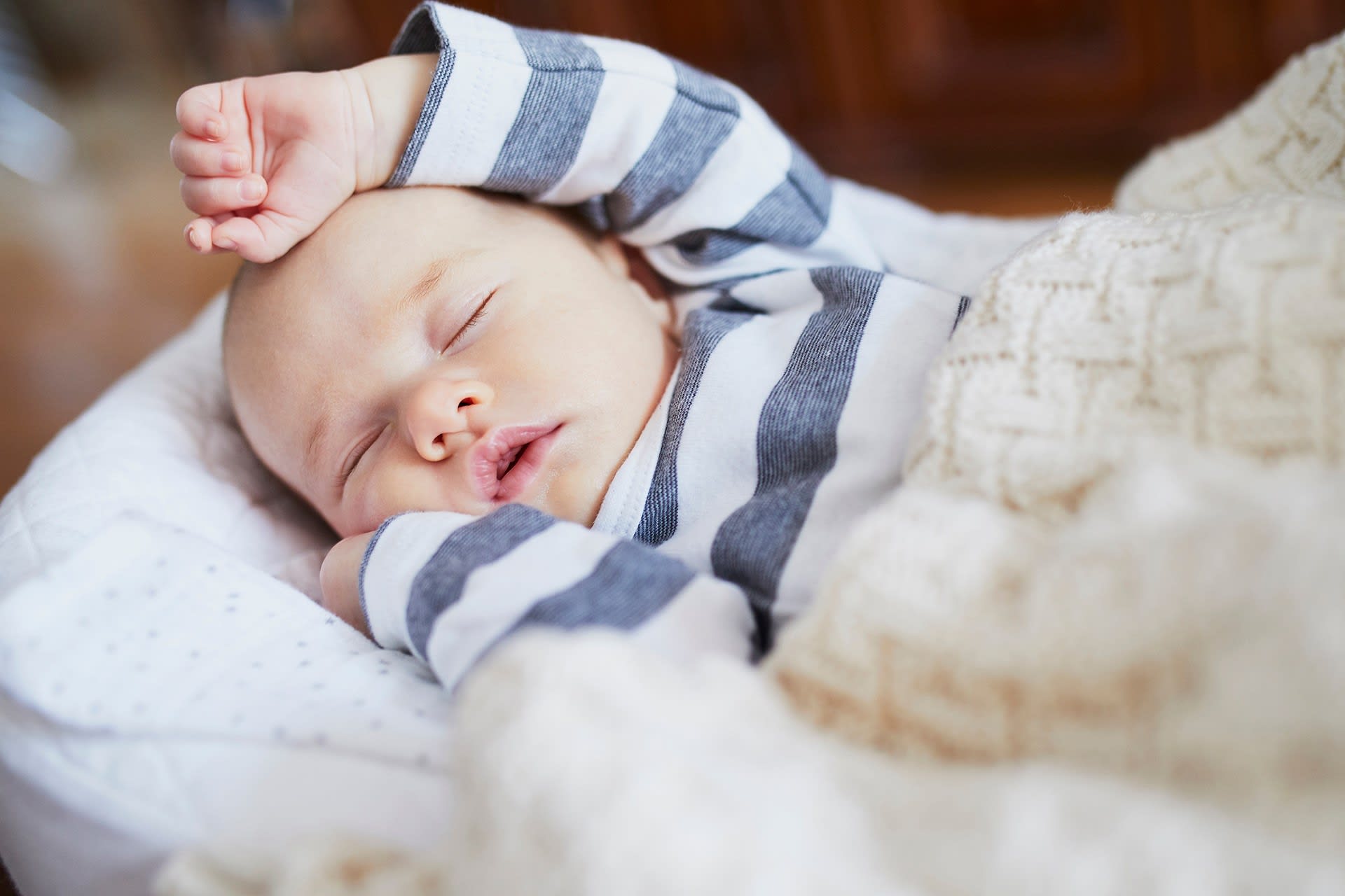 Baby im Herbst richtig anziehen | Baby liegt schlafend auf Decke