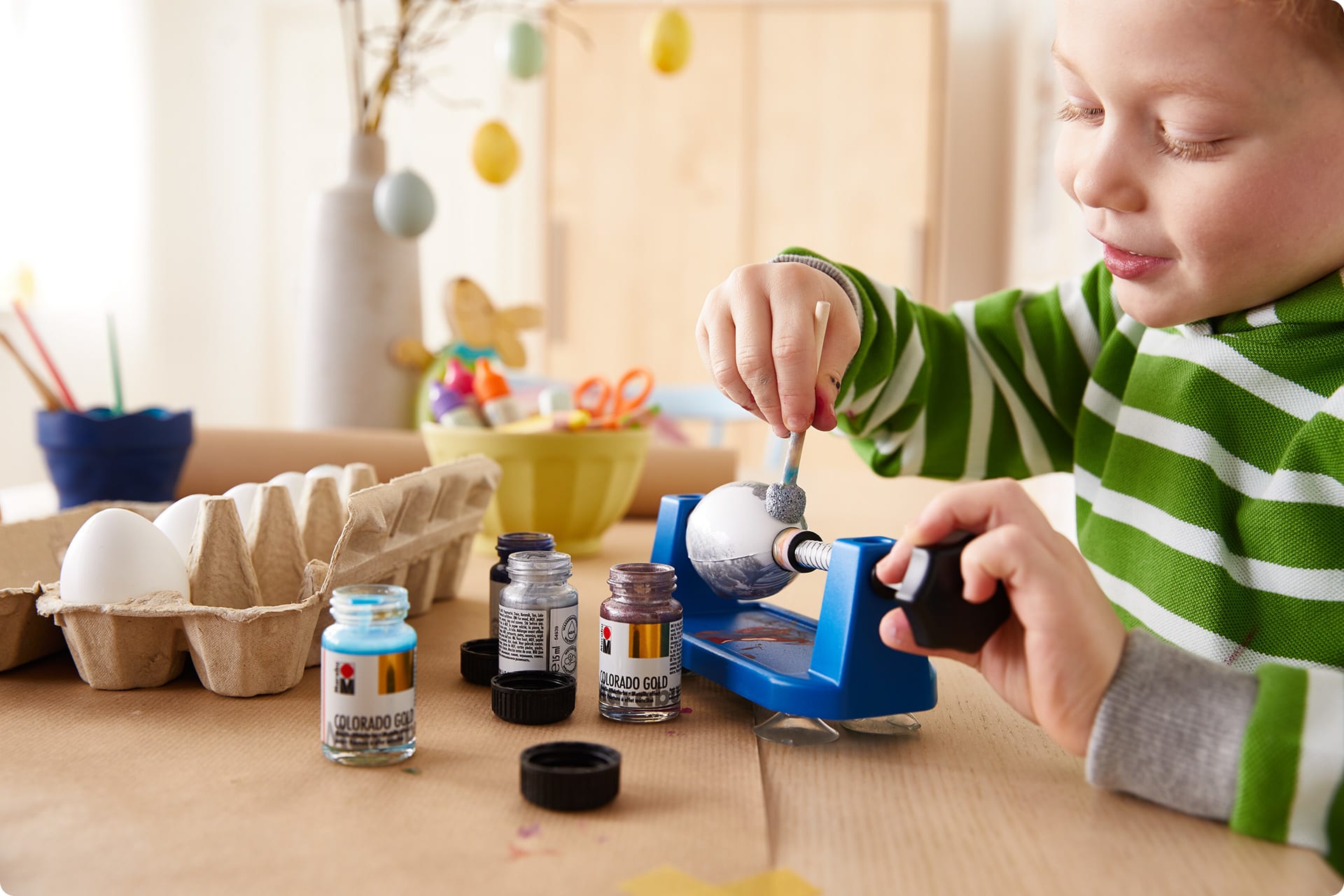 Osterdeko basteln mit Kindern | Junge malt mit Eiermalmaschine