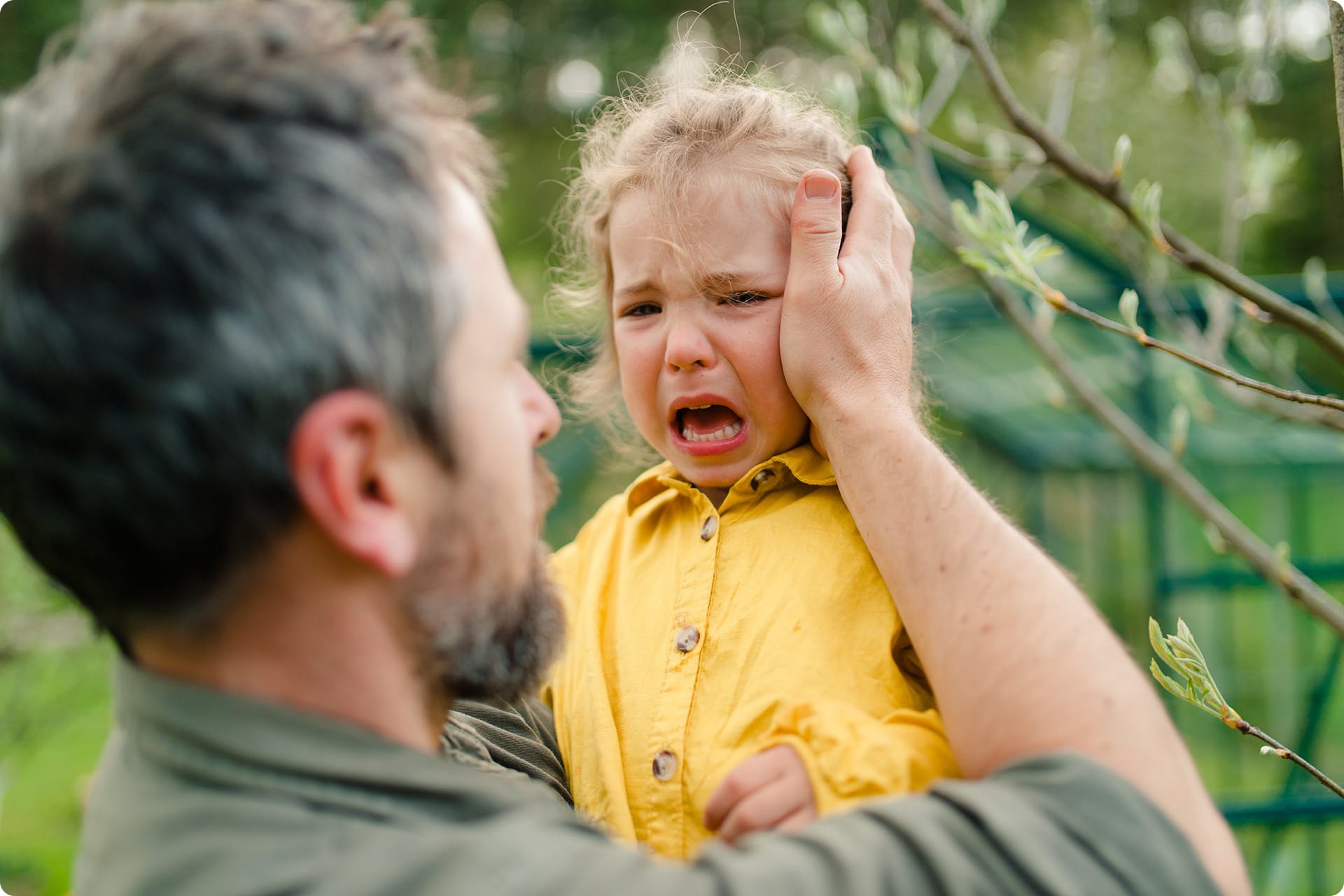 Berliner Modell | Vater hält seine weinende kleine Tochter und tröstet sie im Garten