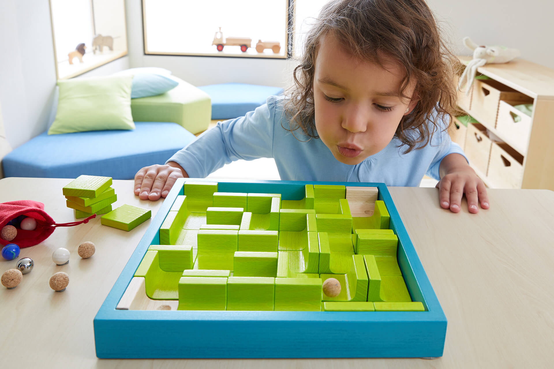 Ein Kind spielt mit dem Sprachförderspiel Murmelspiel.
