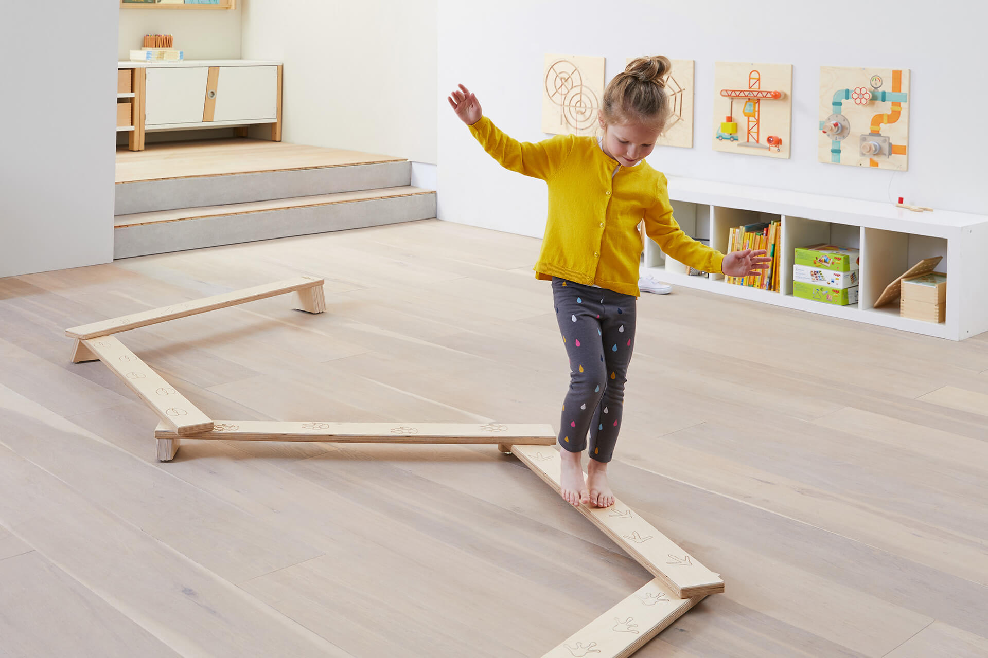Bewegungsraum | Grid | 2 | Image | Balancieren | kleines Mädchen mit gelber Jacke balanciert auf Balancierparcours