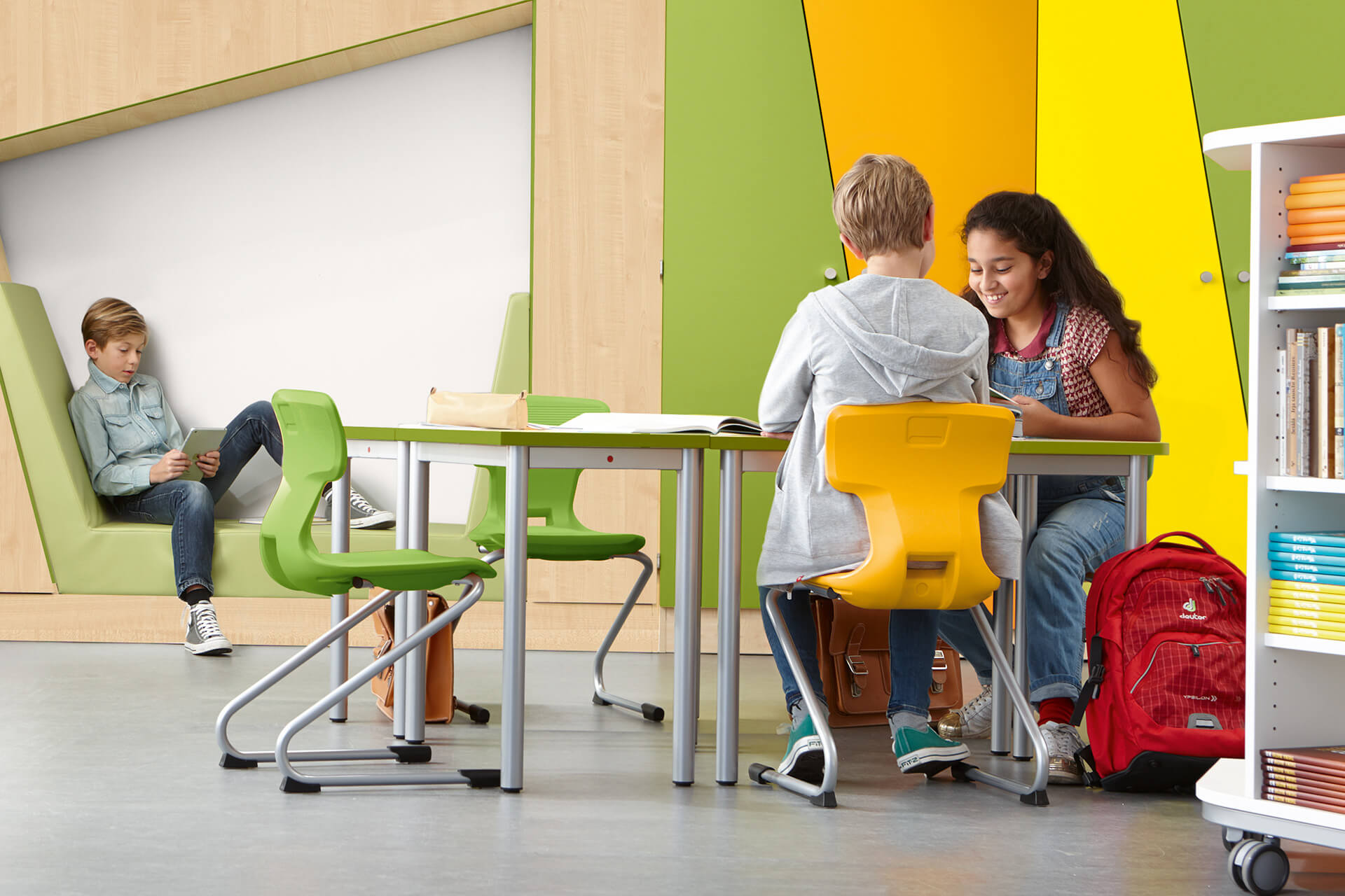 Bibliothek | Grid | 2 | Stühle | Kinder sitzen an einem Tisch mit gelben und hellgrünen Stühlen