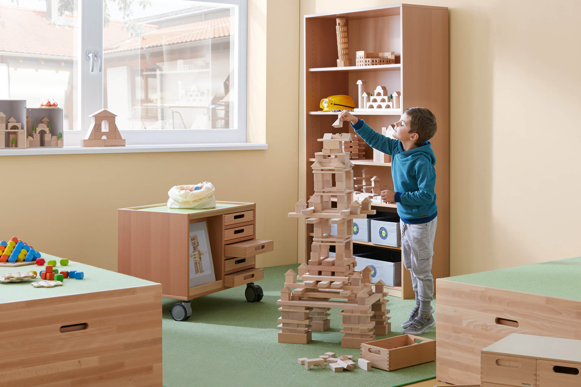 Freizeitraum | Grid | 2 | Spielen | Junge baut mit Holzbausteinen einen Turm 