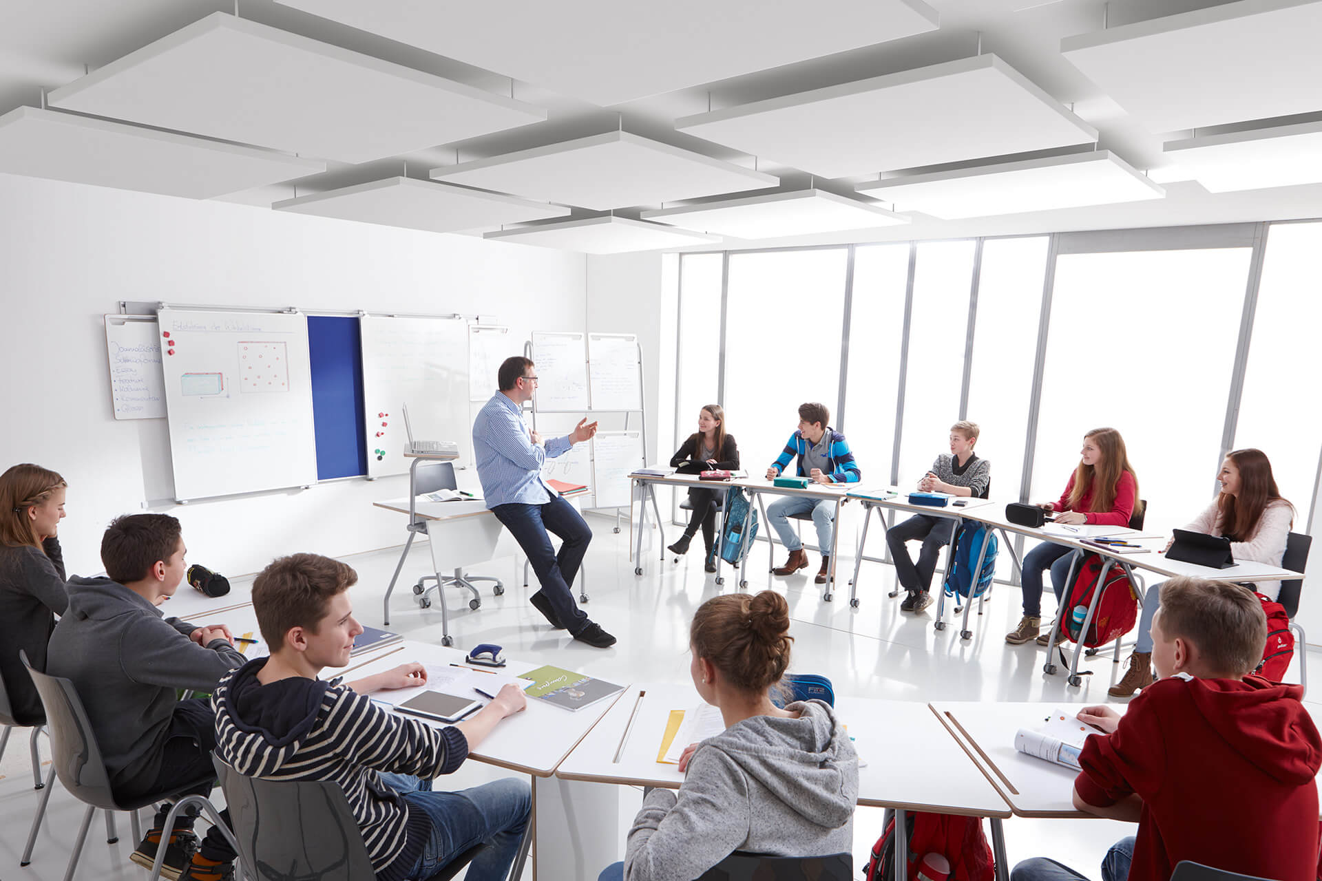 Schule & Hort | Lernräume | Schüler und Lehrer sitzen in einem Klassenraum, Tische stehen in Kreisform