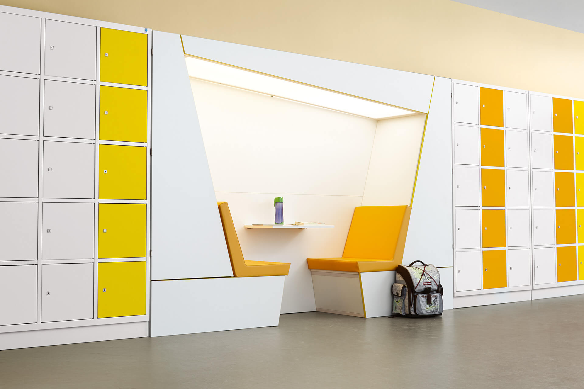 Schule & Hort |Garderoben & Flure | weiß, gelbe Schließfächer mit einer Sitznische in Orange in der Schrankmitte. Büchertasche steht auf dem Boden
