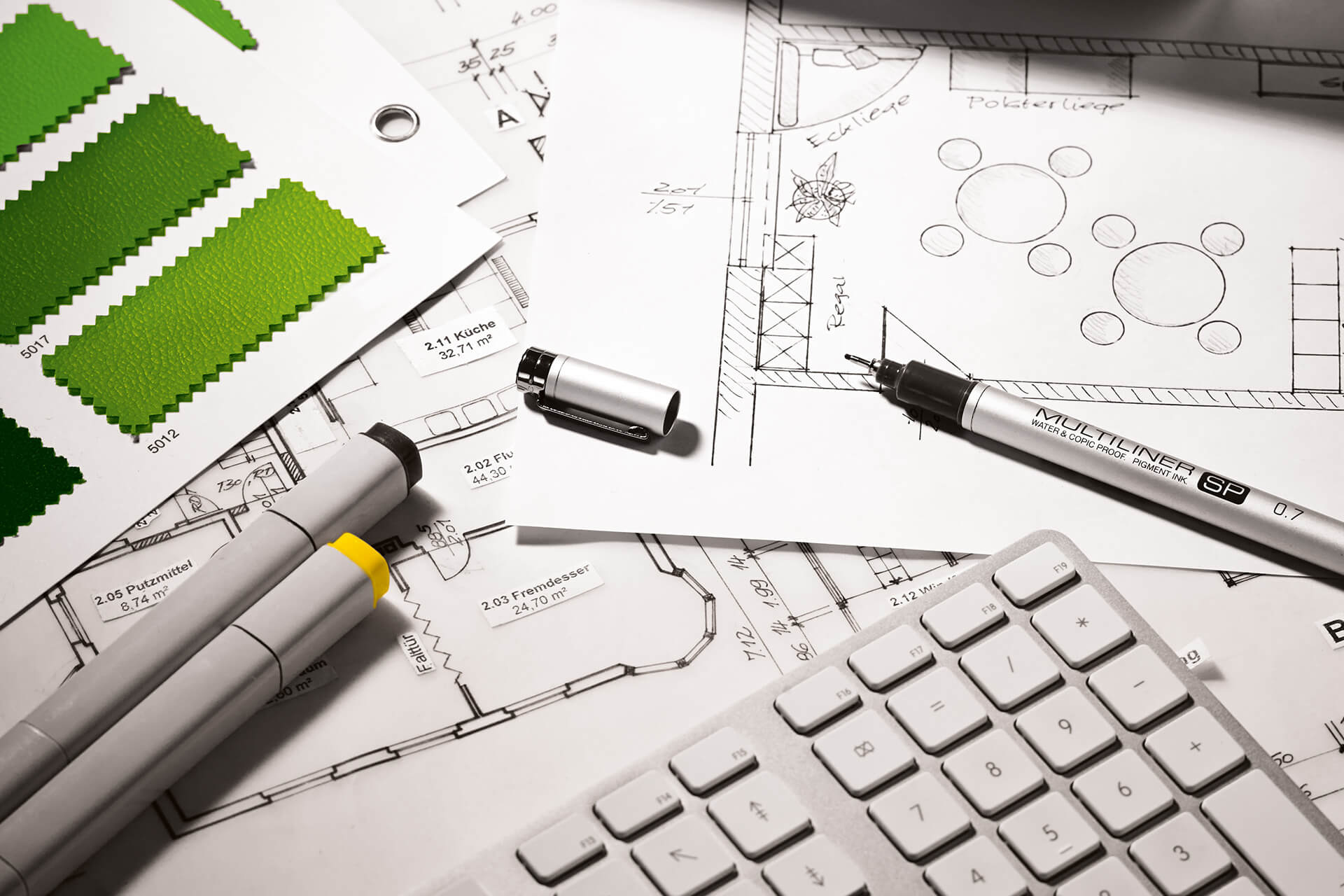 Service-Vorteile  | Planung | Planungszeichnung, Stifte, grüne Stoffmuster liegen neben der Tastatur.