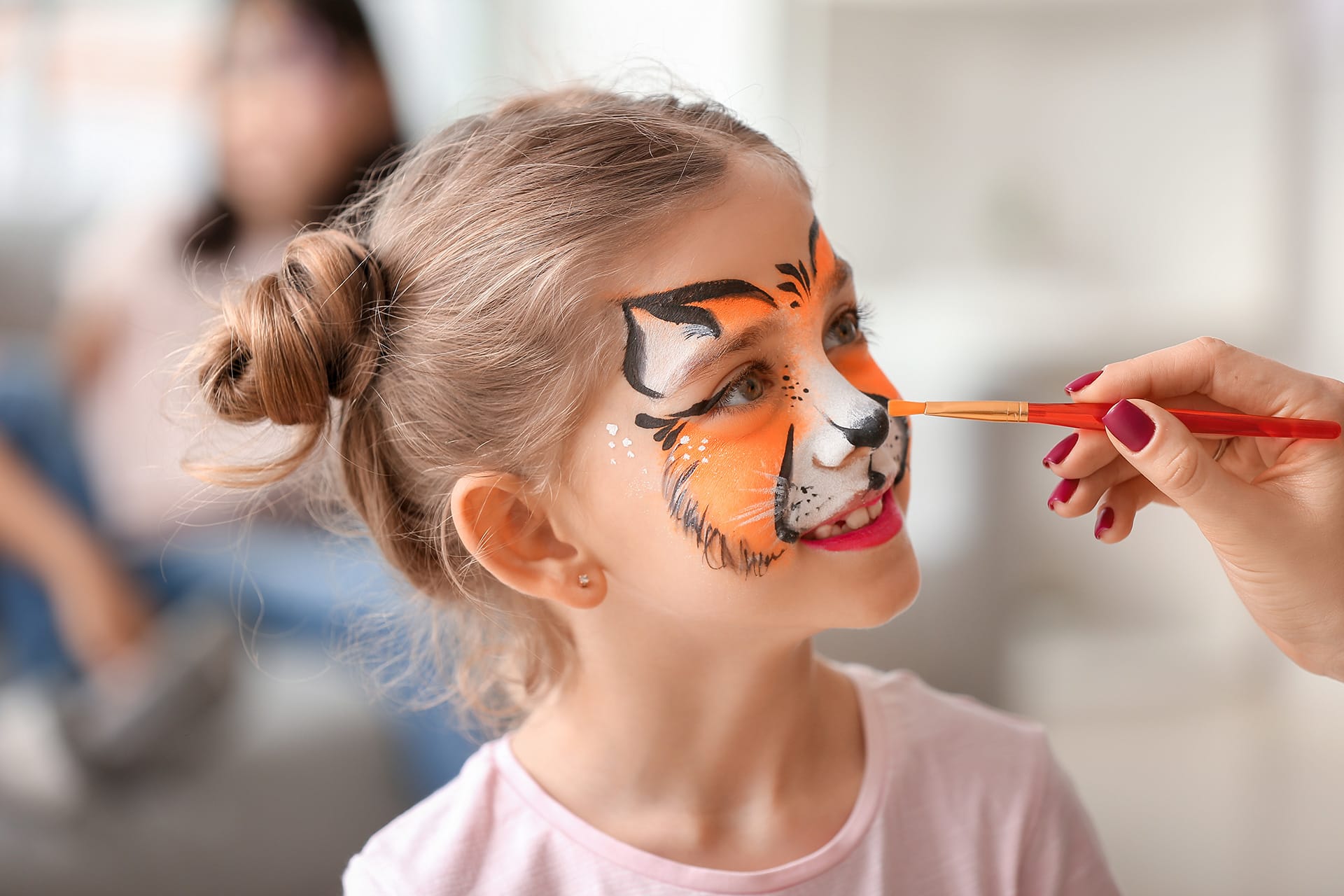 Faschings schminken | image | Mädchen wird mit Pinsel im Gesicht als Tiger geschminkt