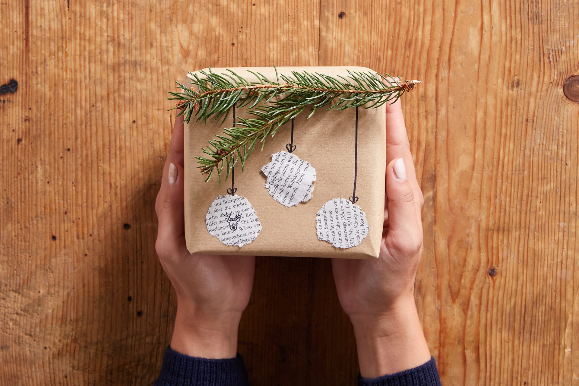 Geschenk-Ideen selbstgemacht | Geschenkpäckchen in braunem Tonkarton gepackt, mit Tannenzweig und Weihnachtsmotiven beklebt.