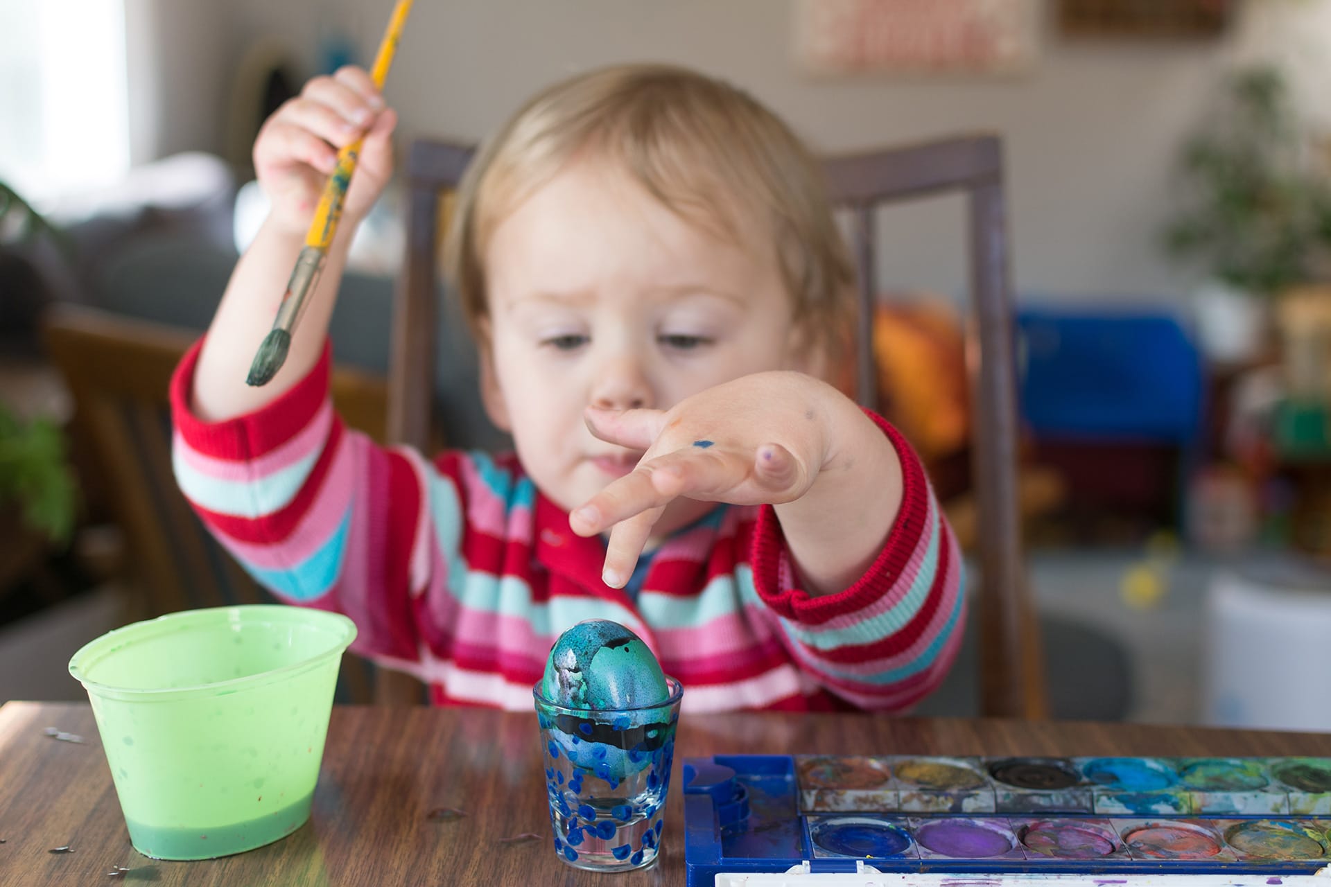 Feinmotorik fördern | Kleinkind bemalt ein Ei mit Wassermalfarben für Ostern
