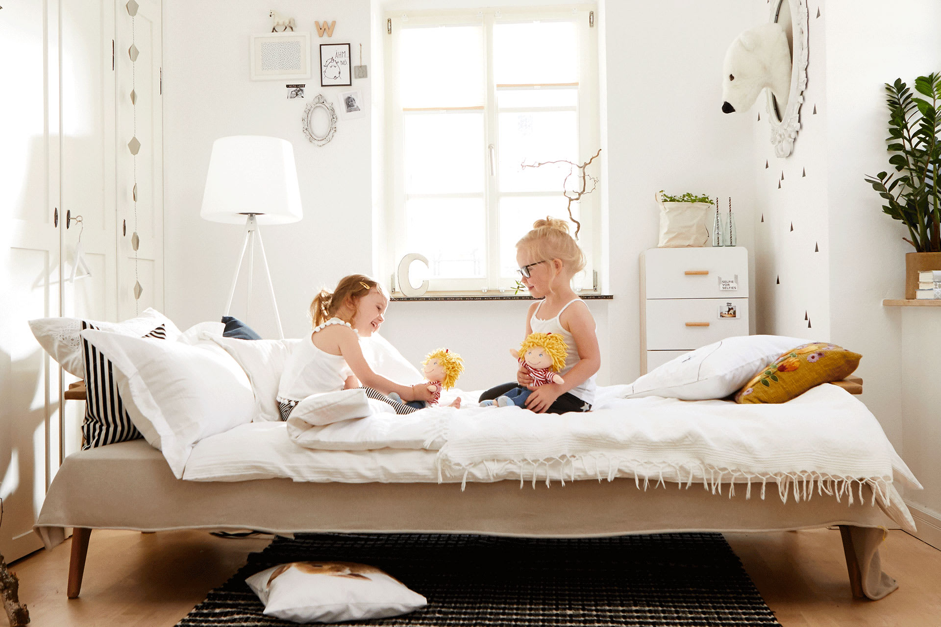 Kinderzimmer teilen – wie lange | Zwei Kinder sitzen auf Bett und spielen
