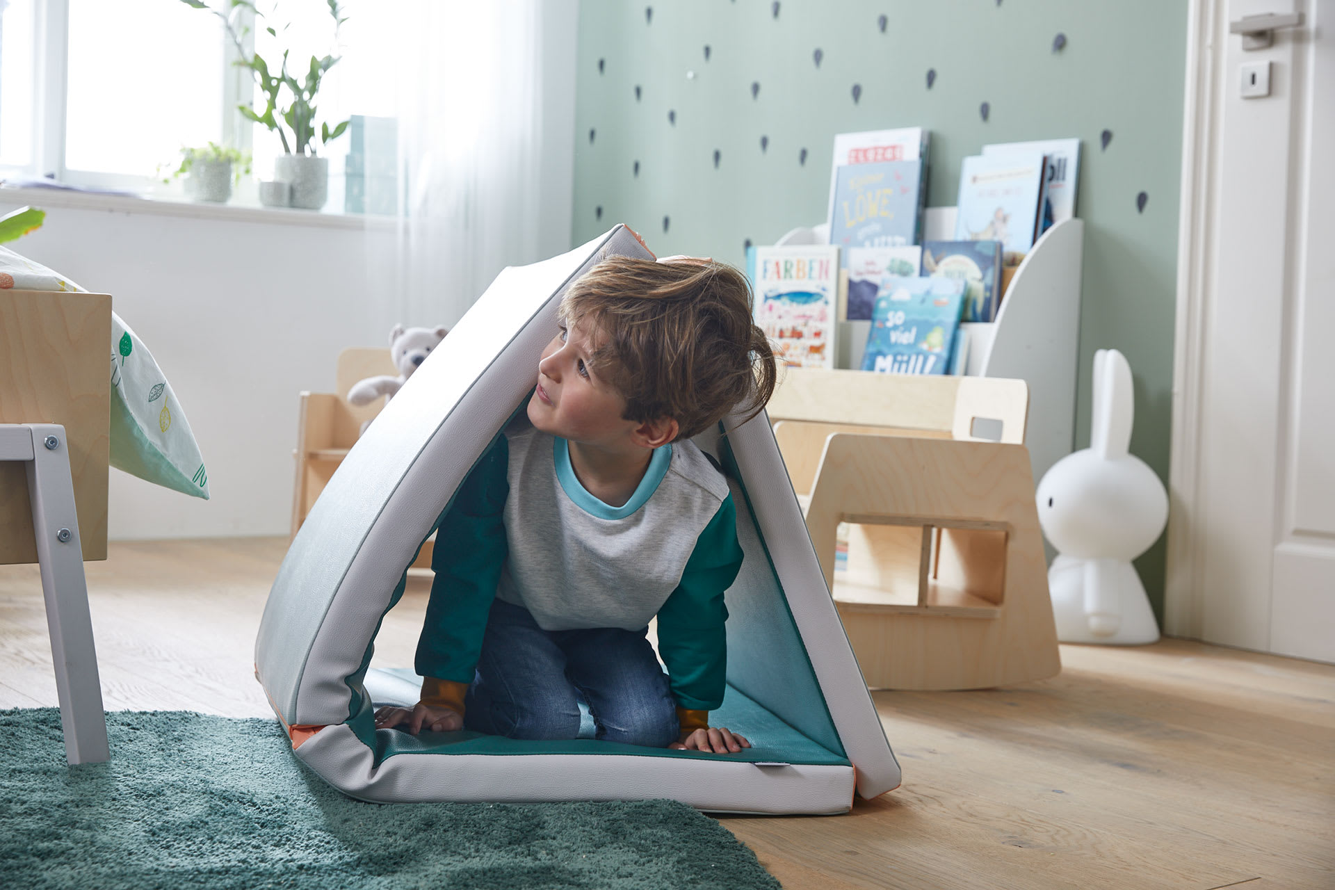  Herbstspiele mit Kindern | Junge sitzt zwischen eingeklappter Matte 