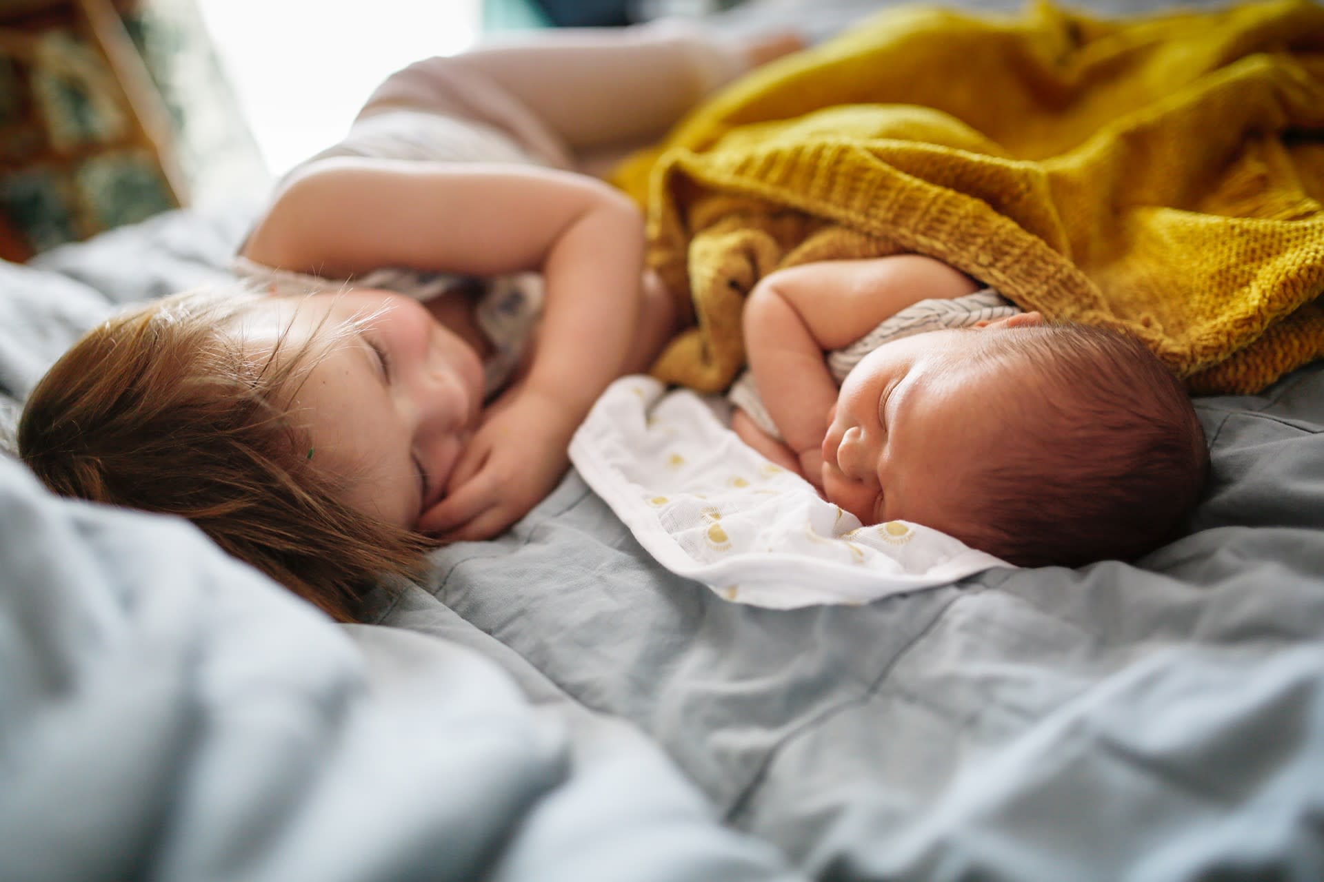 Schlaflieder für Kinder | Baby und kleines Kind liegen zusammen im Bett.