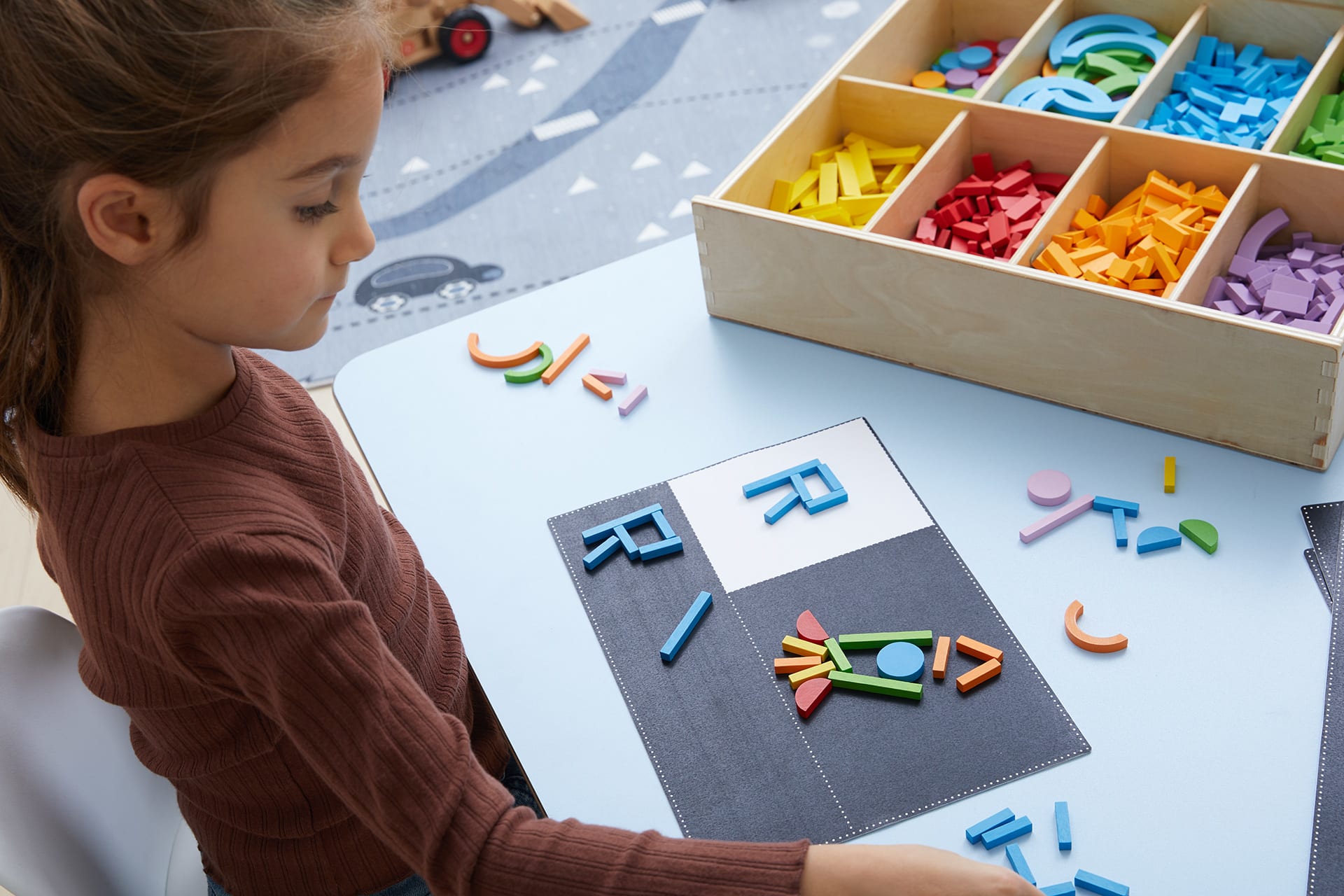 Fröbel Kindergarten | Mädchen legt bunte Buchstaben aus Holzteilen und Bilder