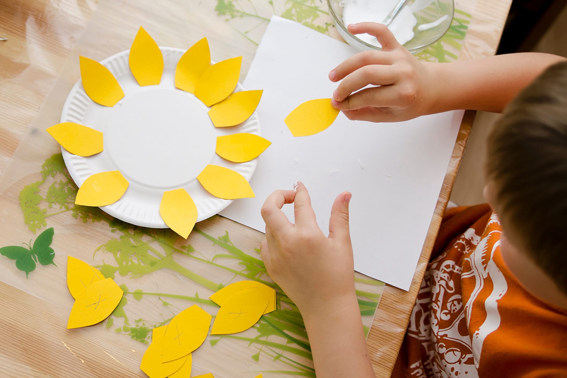 Geburtstagstipps September | Kind klebt gelbe Papierblüten auf einem Pappteller