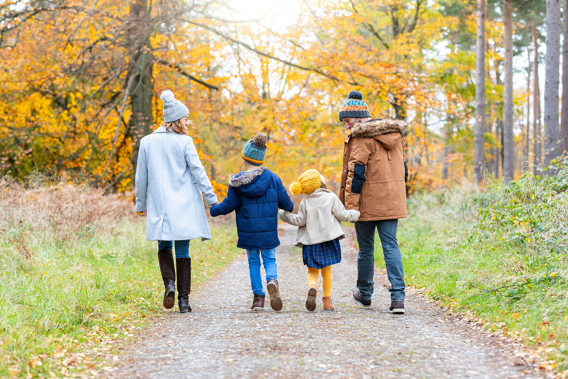 Kinder im Herbst richtig anziehen | Familie läuft zusammen im Wald