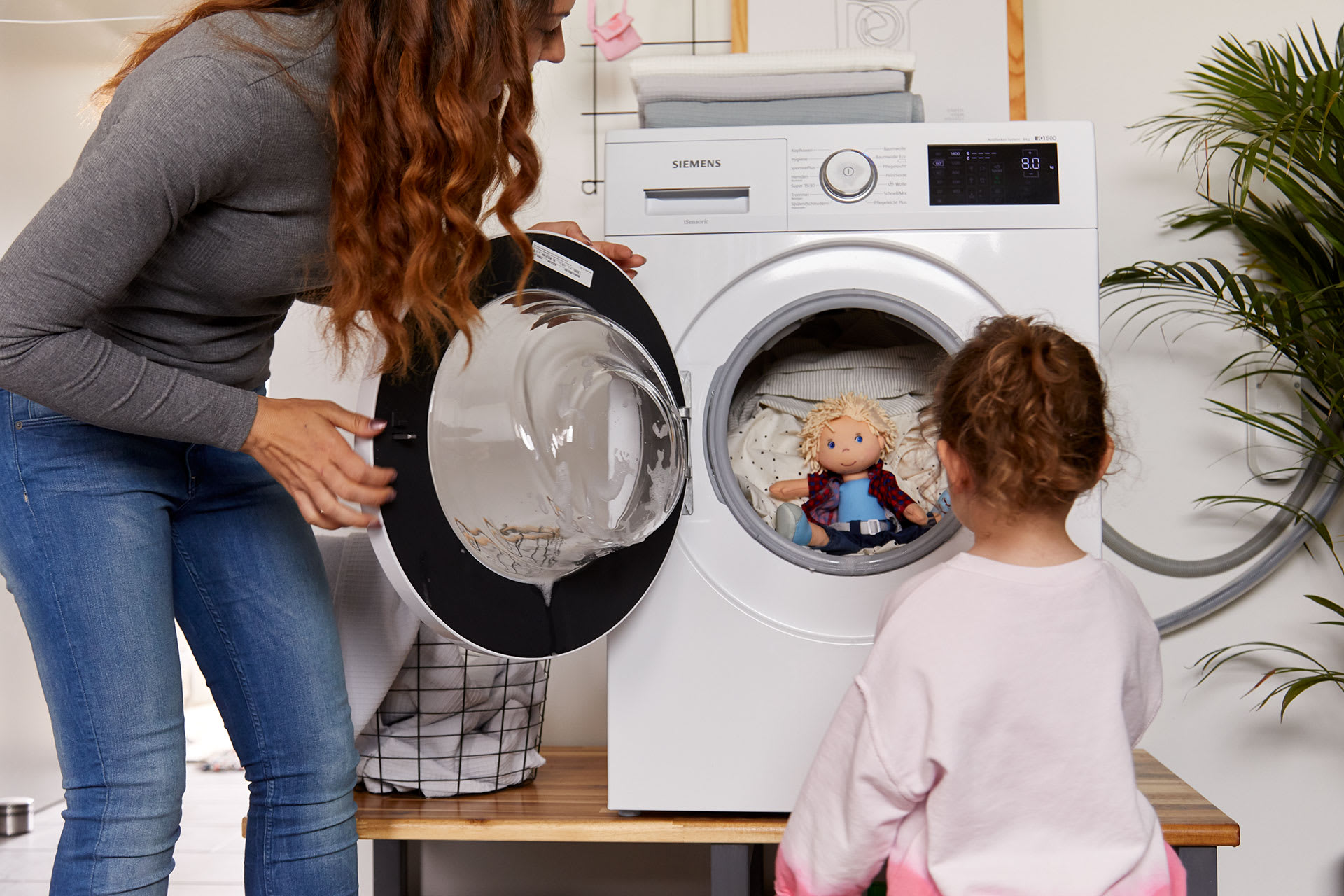 Familienzusammenhalt | Kind und Mutter vor einer Waschmaschine