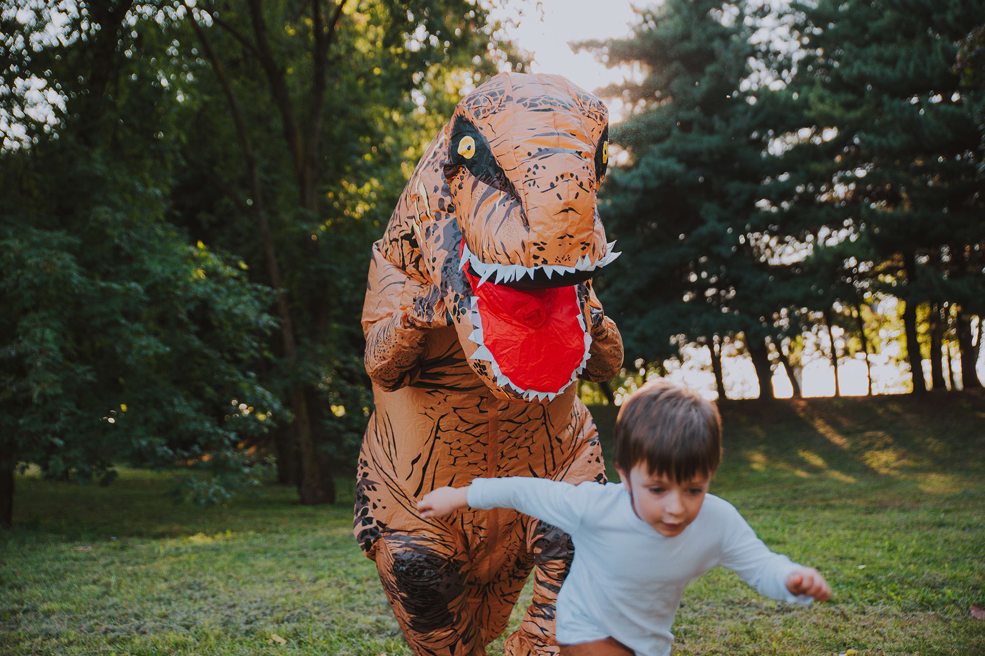 Rollenspiele | Vater und Sohn spielen im Park, mit einem Dinosaurier-Kostüm, 