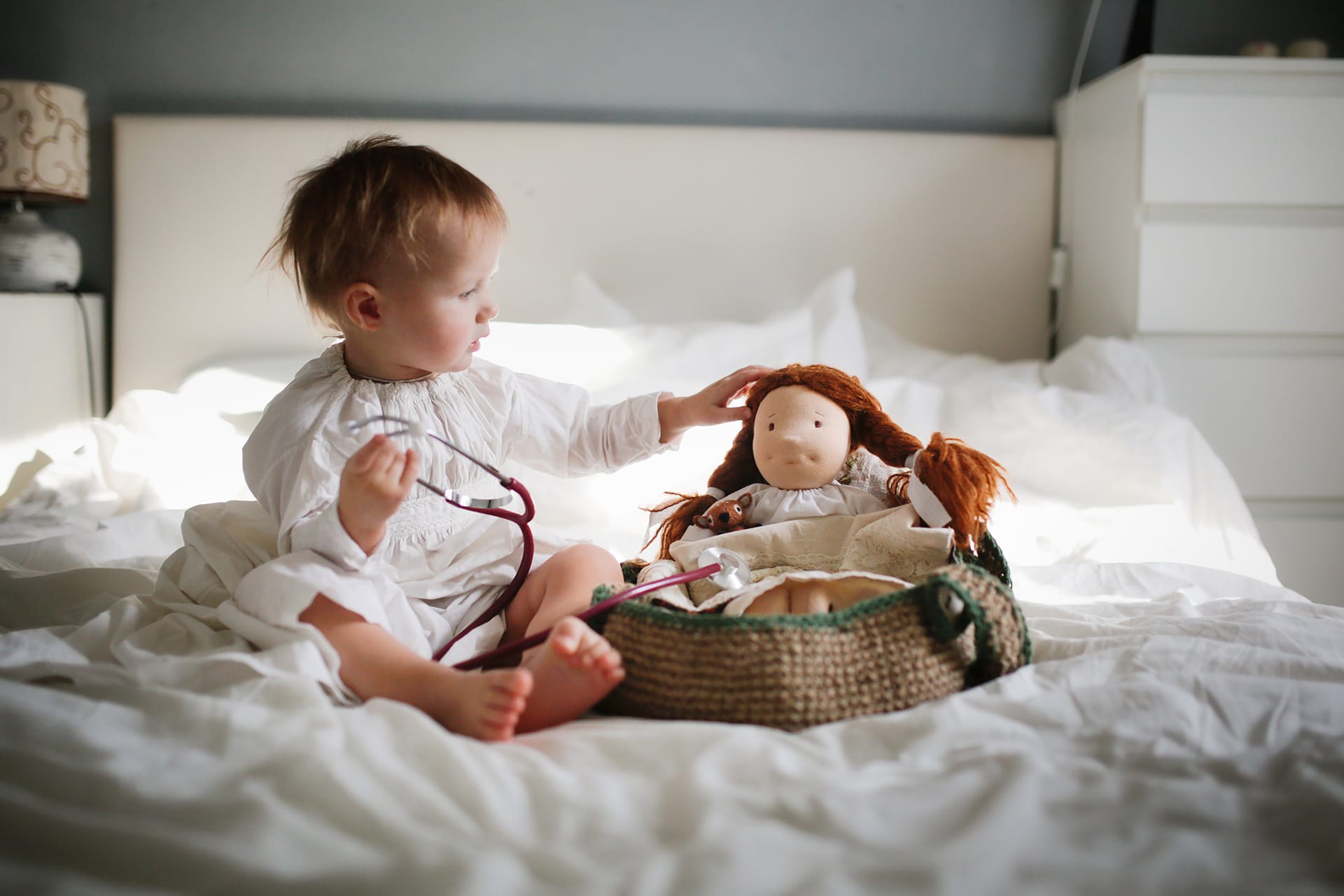 Rollenspiele | Kleinkind hört mit Stethoskop zu einer Puppe Spielzeug im Bett im Schlafzimmer