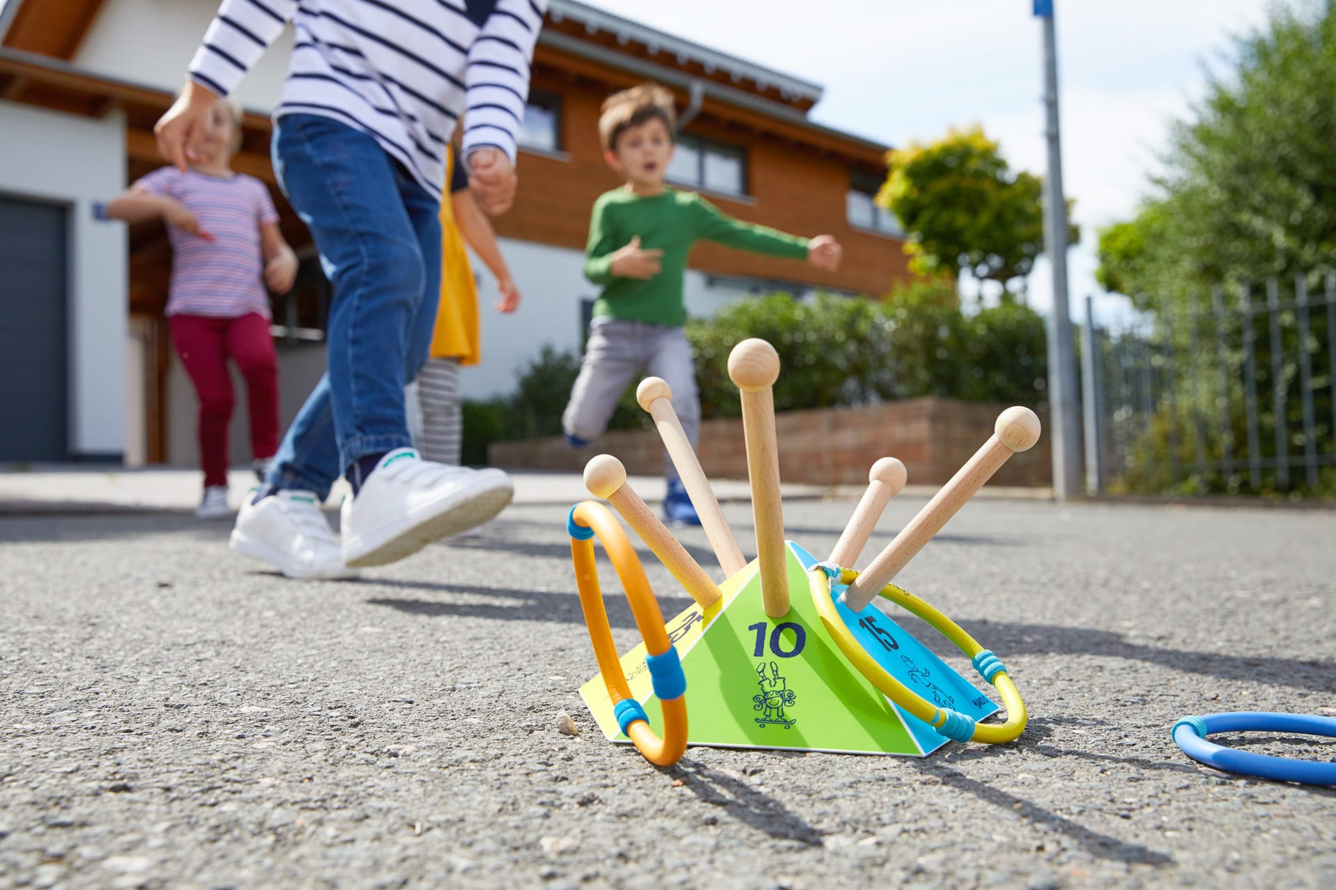 Spiele für draußen | Kinder werfen Holzspielreifen auf Holzstangen, draußen im Hof