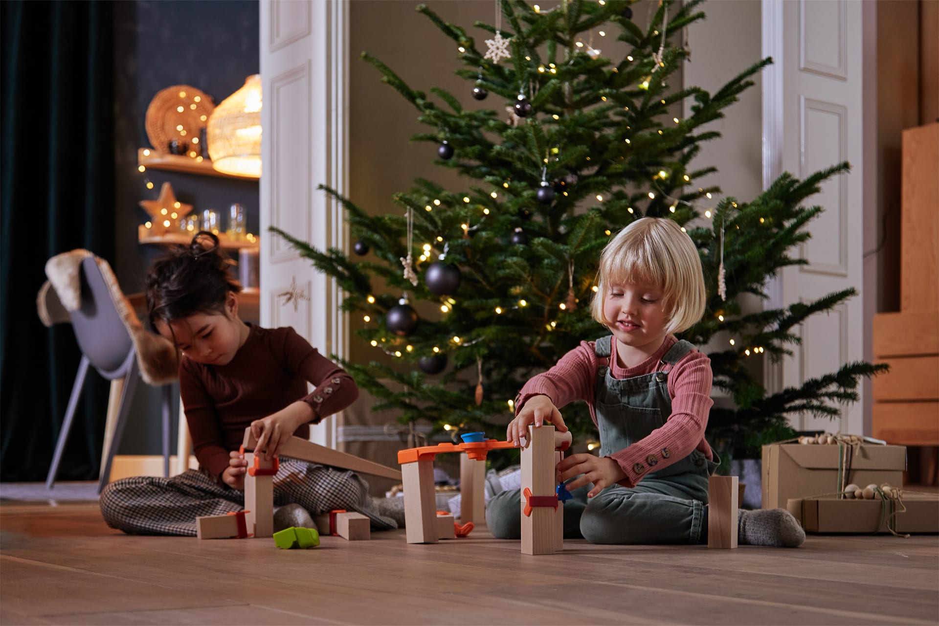 Exklusive Geschenketipps von HABA für das Weihnachtsfest | 2 Kinder spielen vor dem Tannenbaum mit Kugelbahn