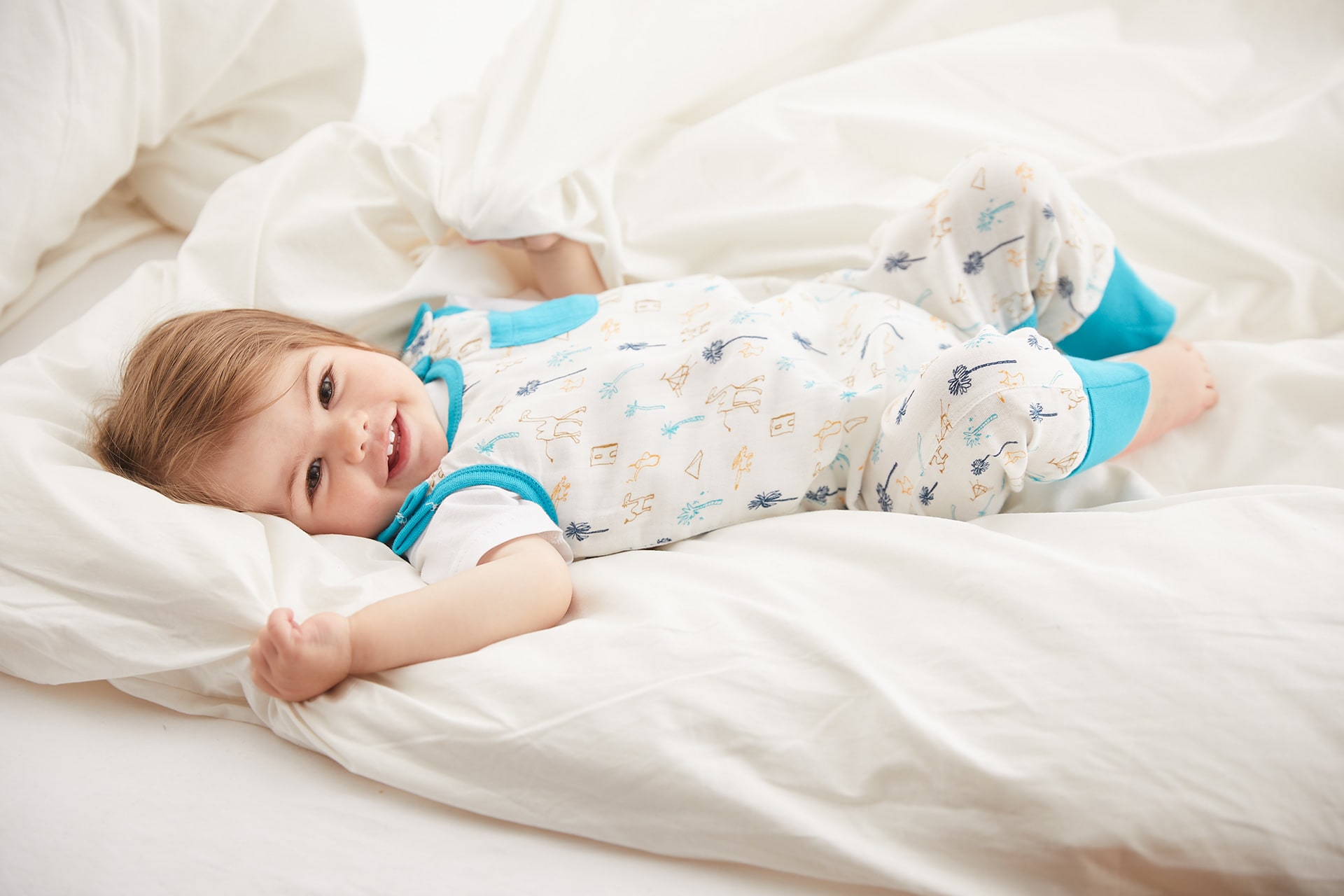 Babys im Frühling richtig anziehen | Baby im Strampler Musselin von HABA liegt auf dem Bett