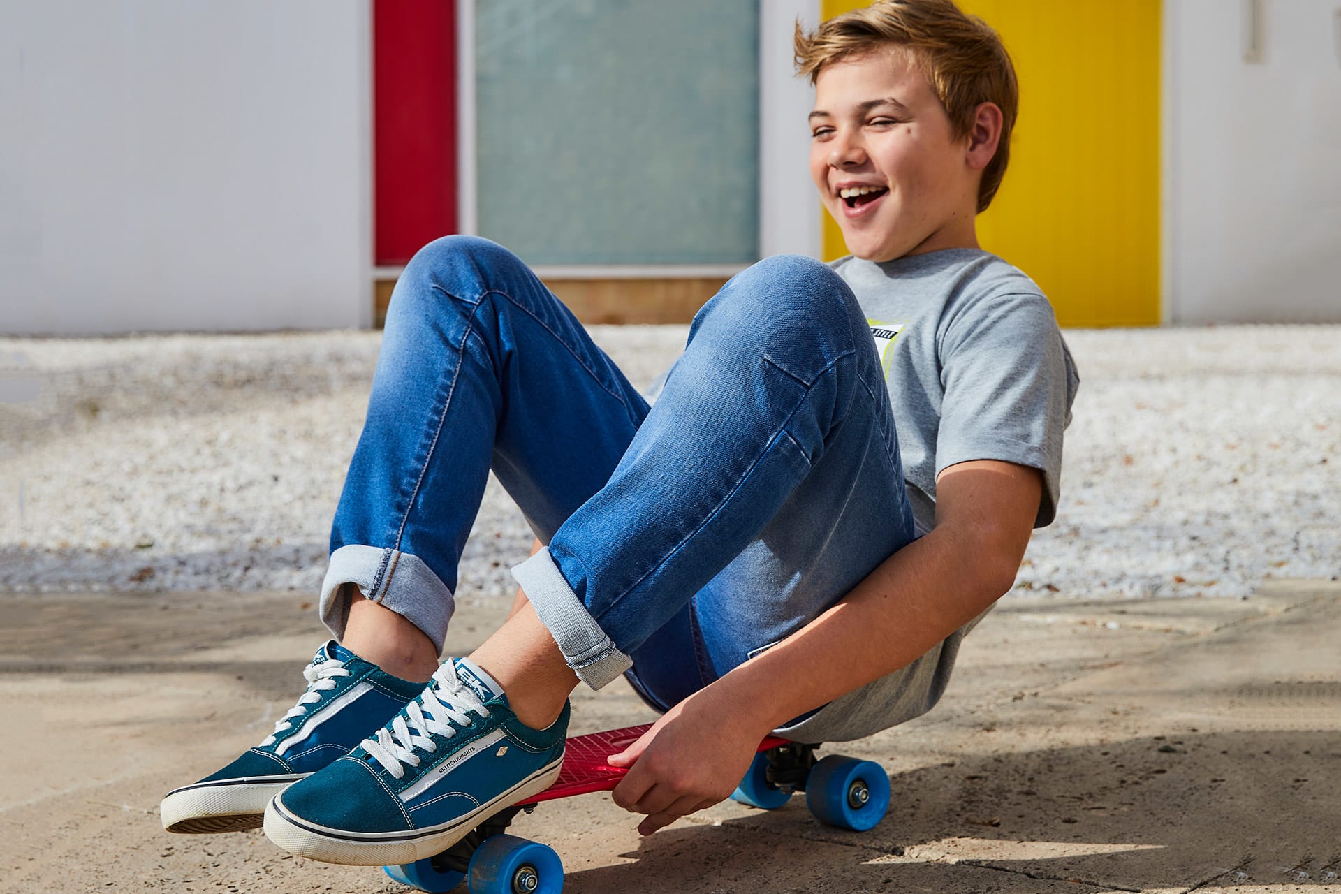 Bewegungsspiele Kinder | Junge sitzt auf einem Skateboard