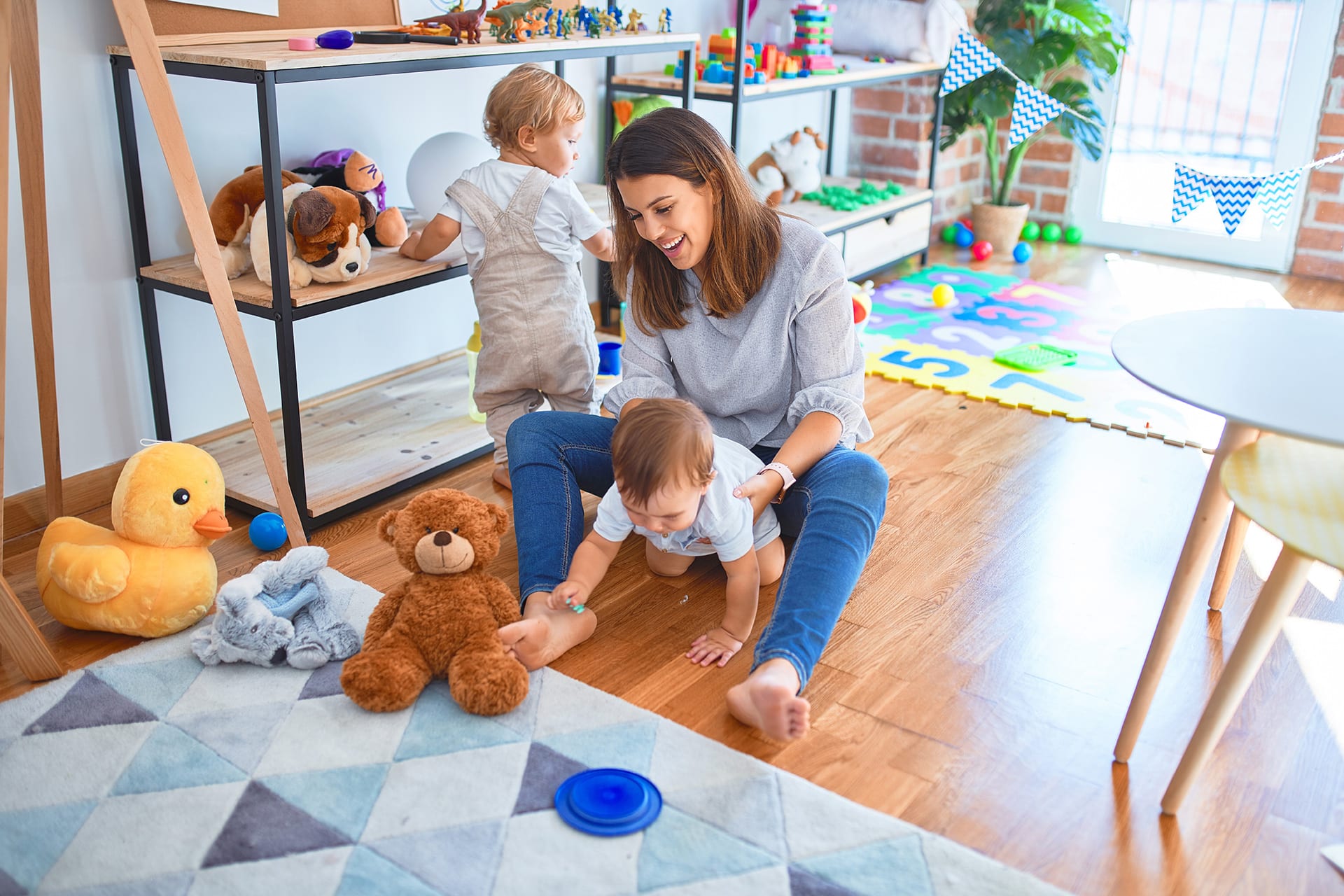 Welcher Kindergarten ist der richtige | Lehrerin und Kleinkinder spielen im Kindergarten mit vielen Spielsachen