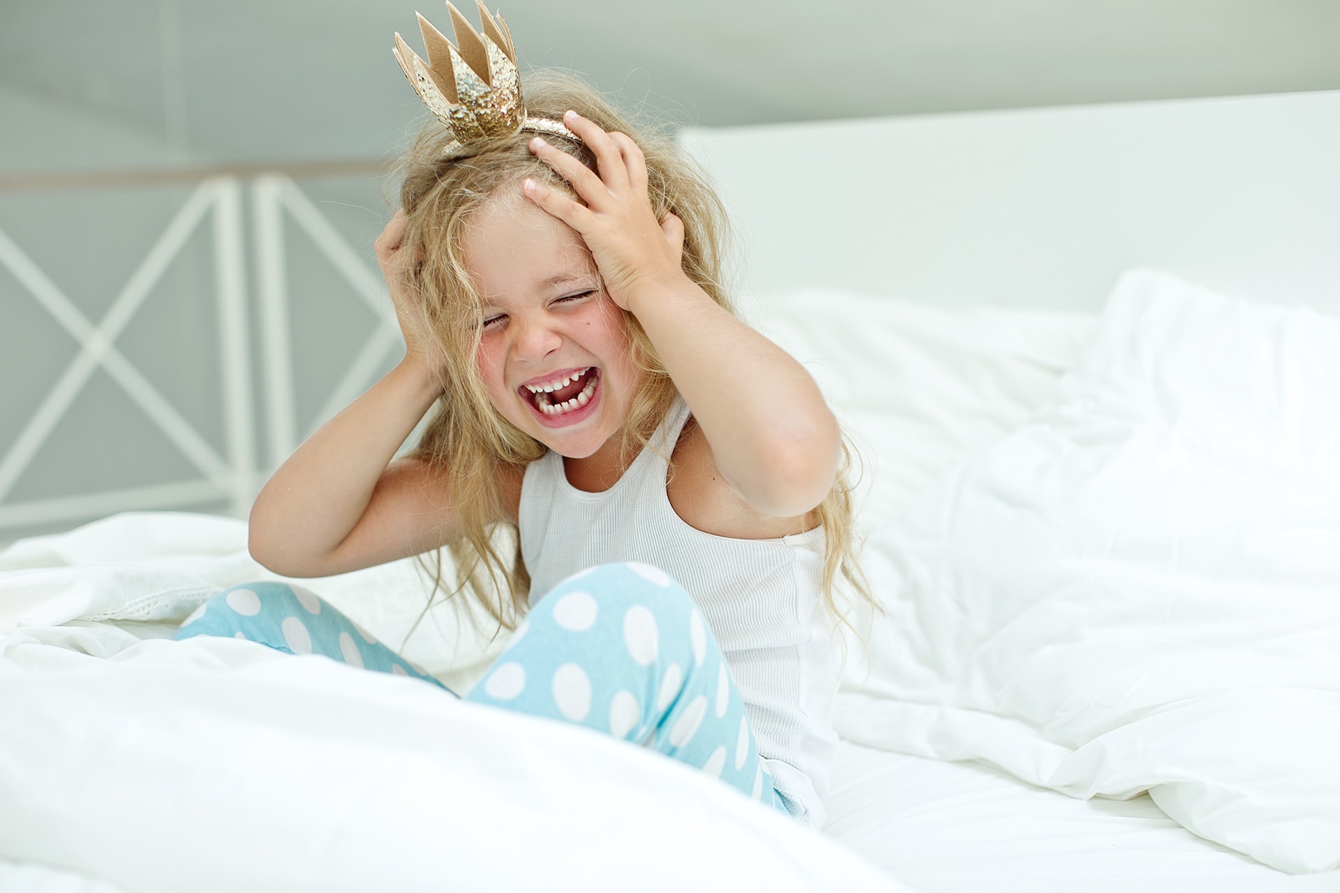 Konzentrationsstörungen bei Kindern |  Mädchen sitzt im Bett schreit und hält sich Hände an Kopf
