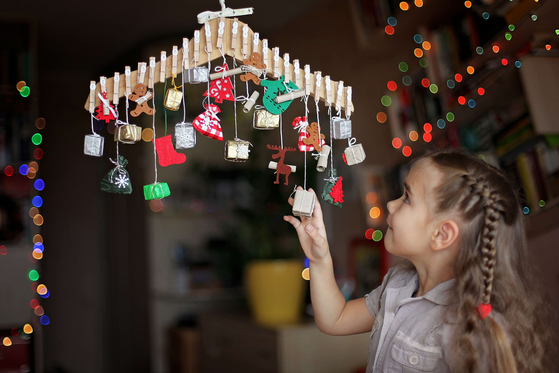 Adventskalender basteln | Kind sieht sich Adventskalender am Kleiderbügel an