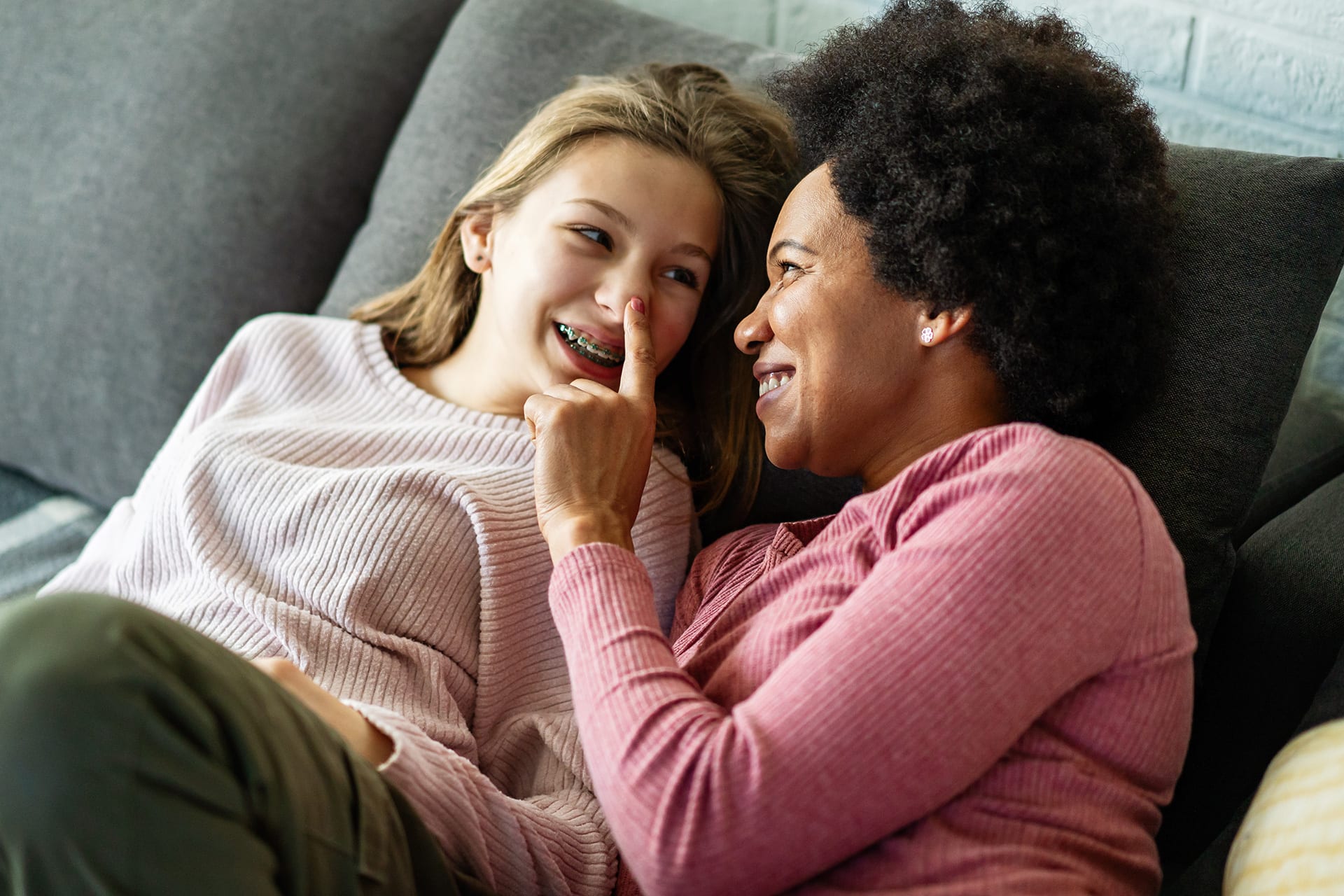 Kind aufklären | Mutter und Tochter liegen auf dem Sofa