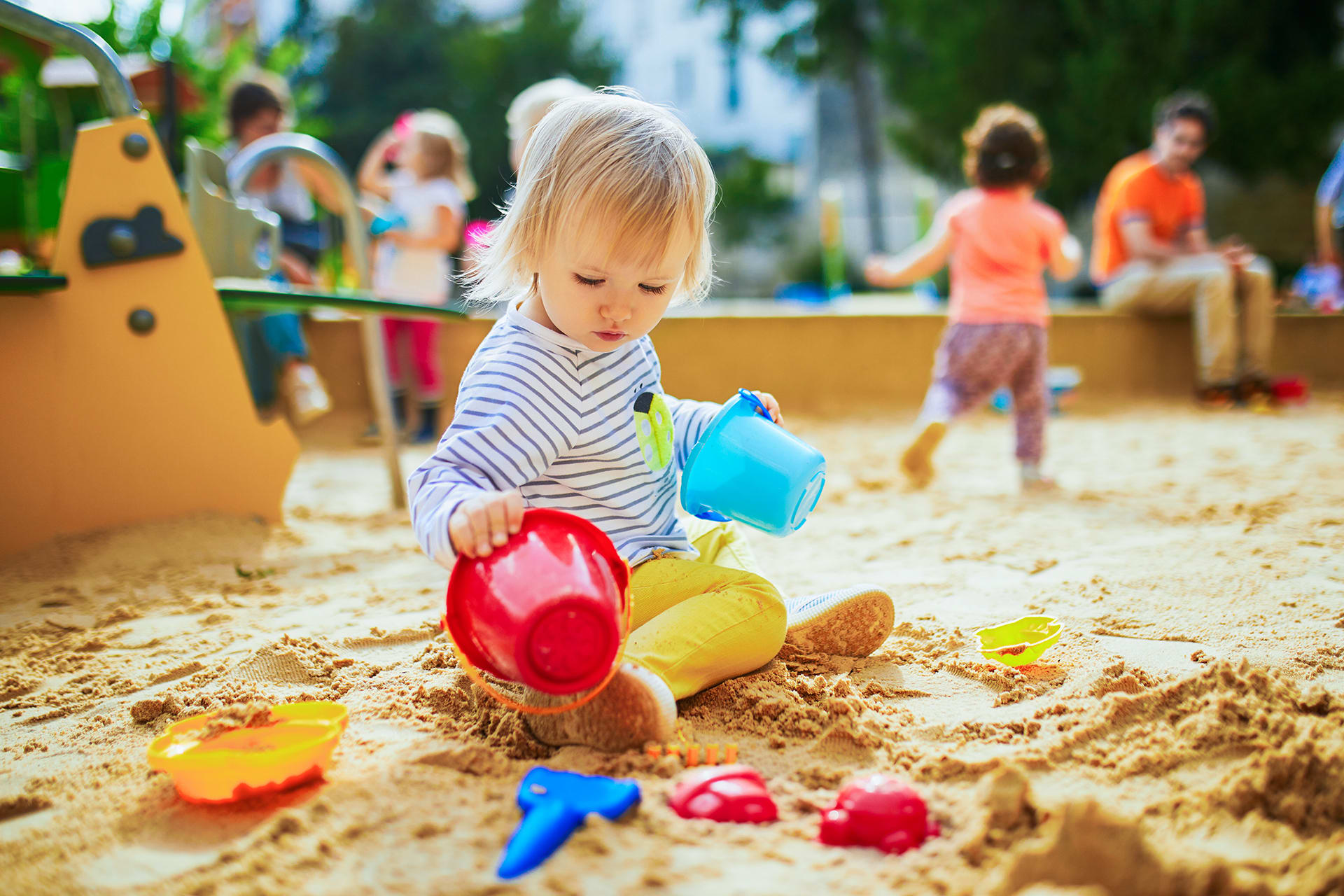 Baby Entwicklung Monat 16 | kleines Mädchen auf dem Spielplatz im Sandkasten