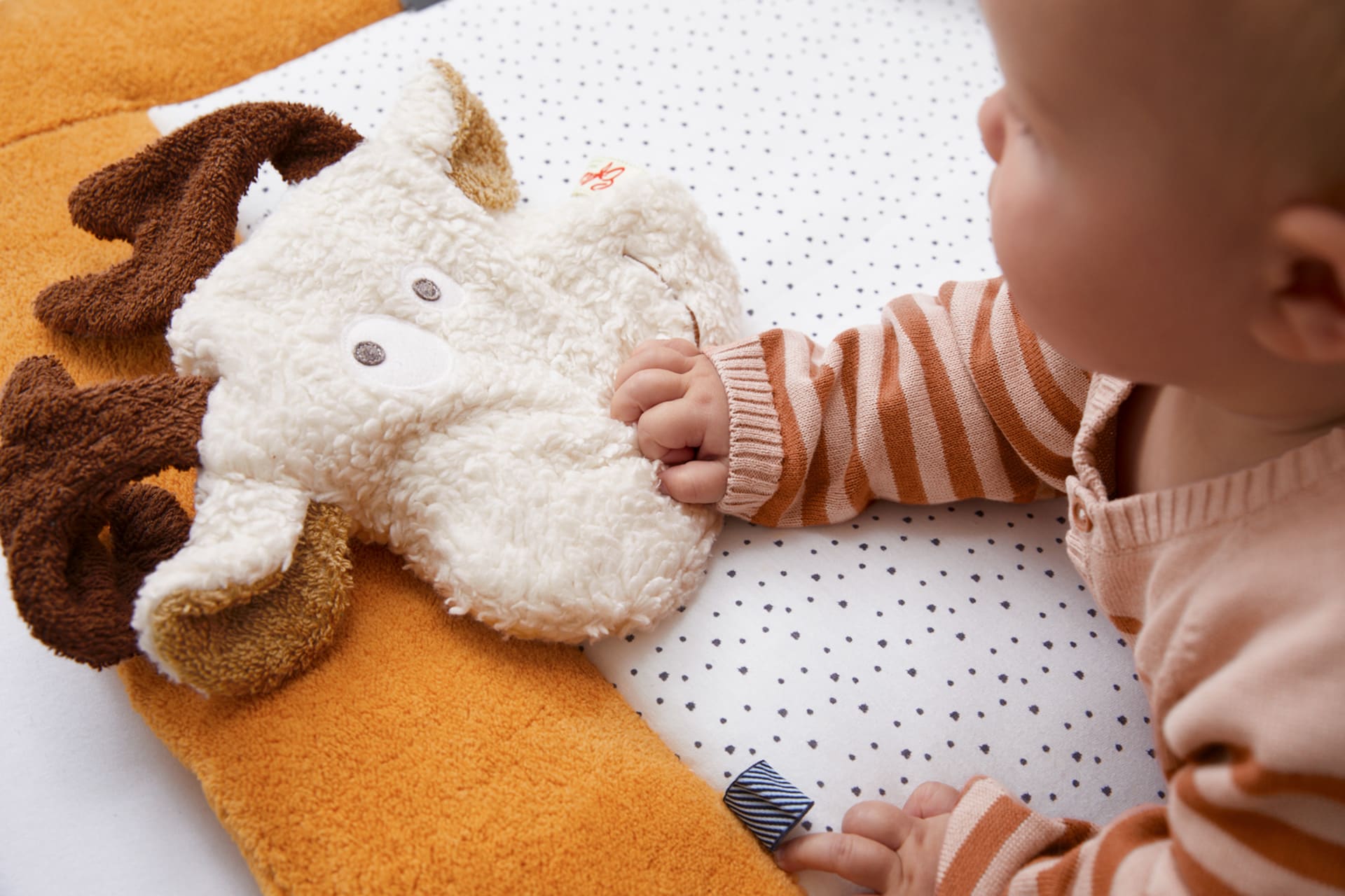 Spielerisch lernen |  Baby legt Hand auf Rehkissen