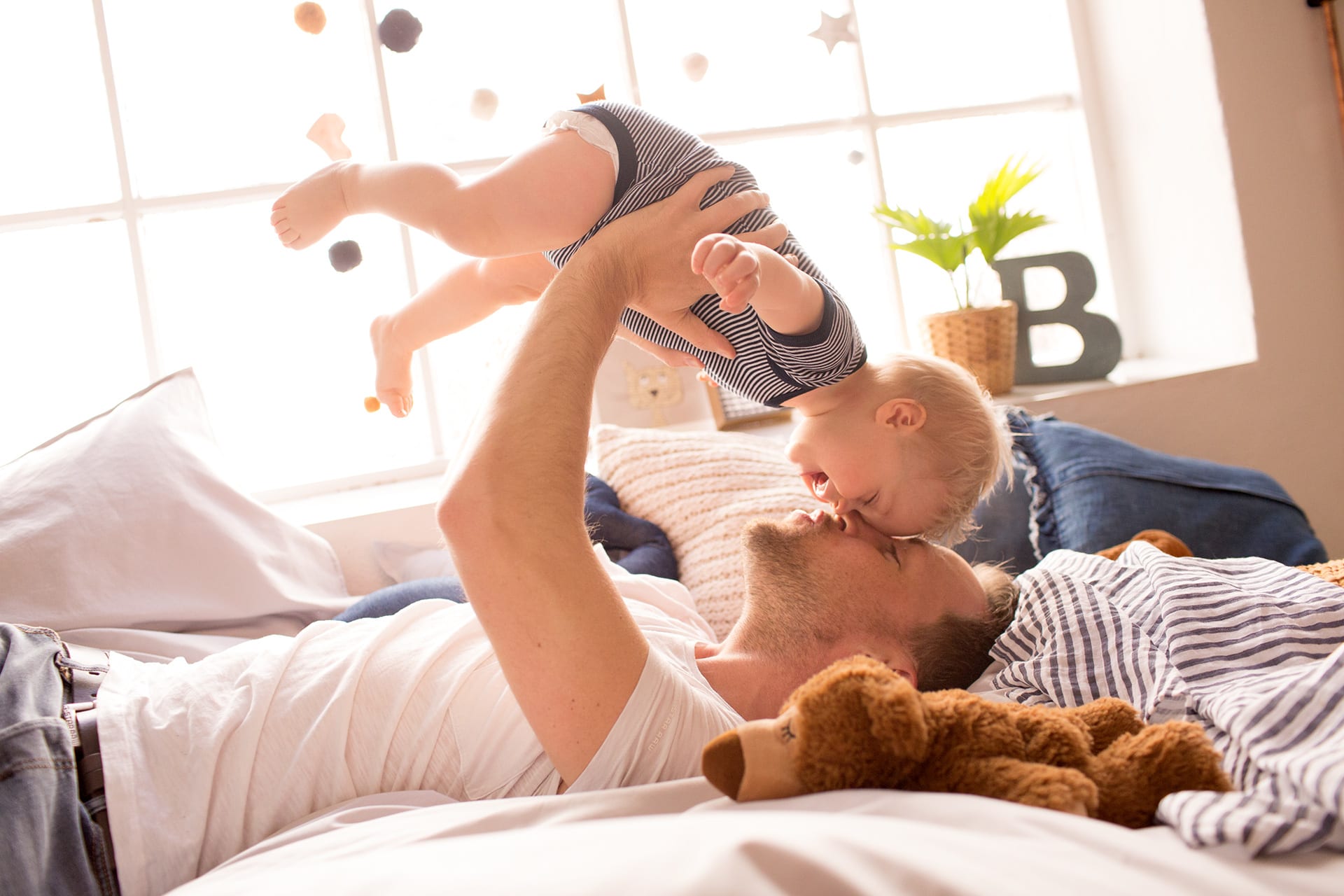 Baby zum Lachen bringen | liegender Vater hält lachendes Baby in die Luft