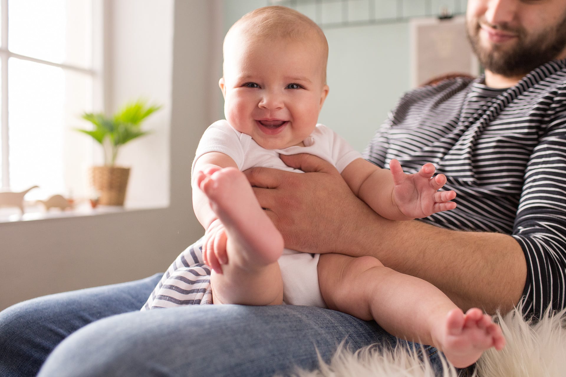 Baby zum Lachen bringen | Baby sitzt auf Schoss von Vater und lacht