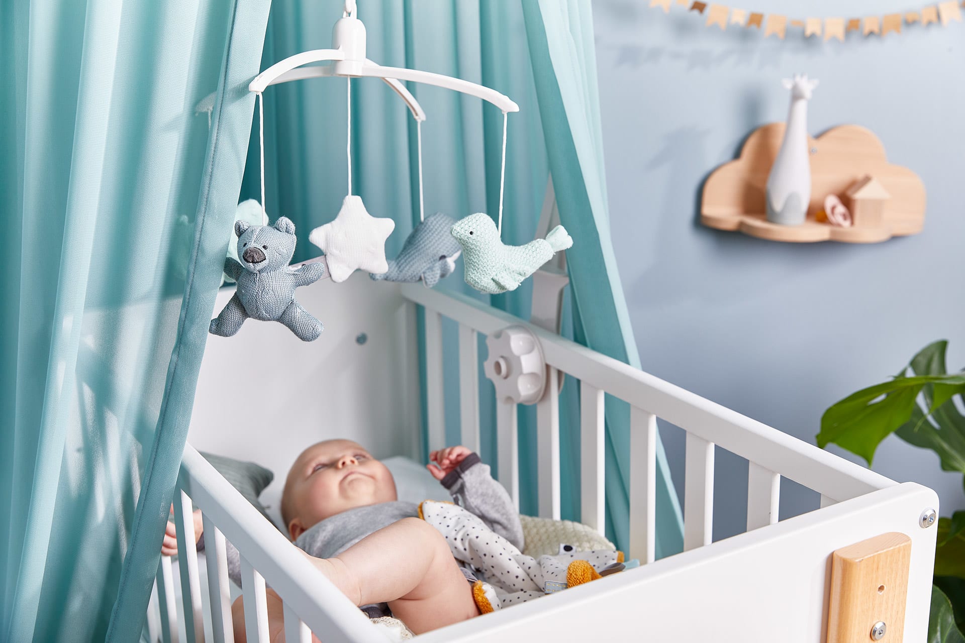 Babyzimmer gestalten | Baby liegt im Babybett und schaut sich Mobile an.