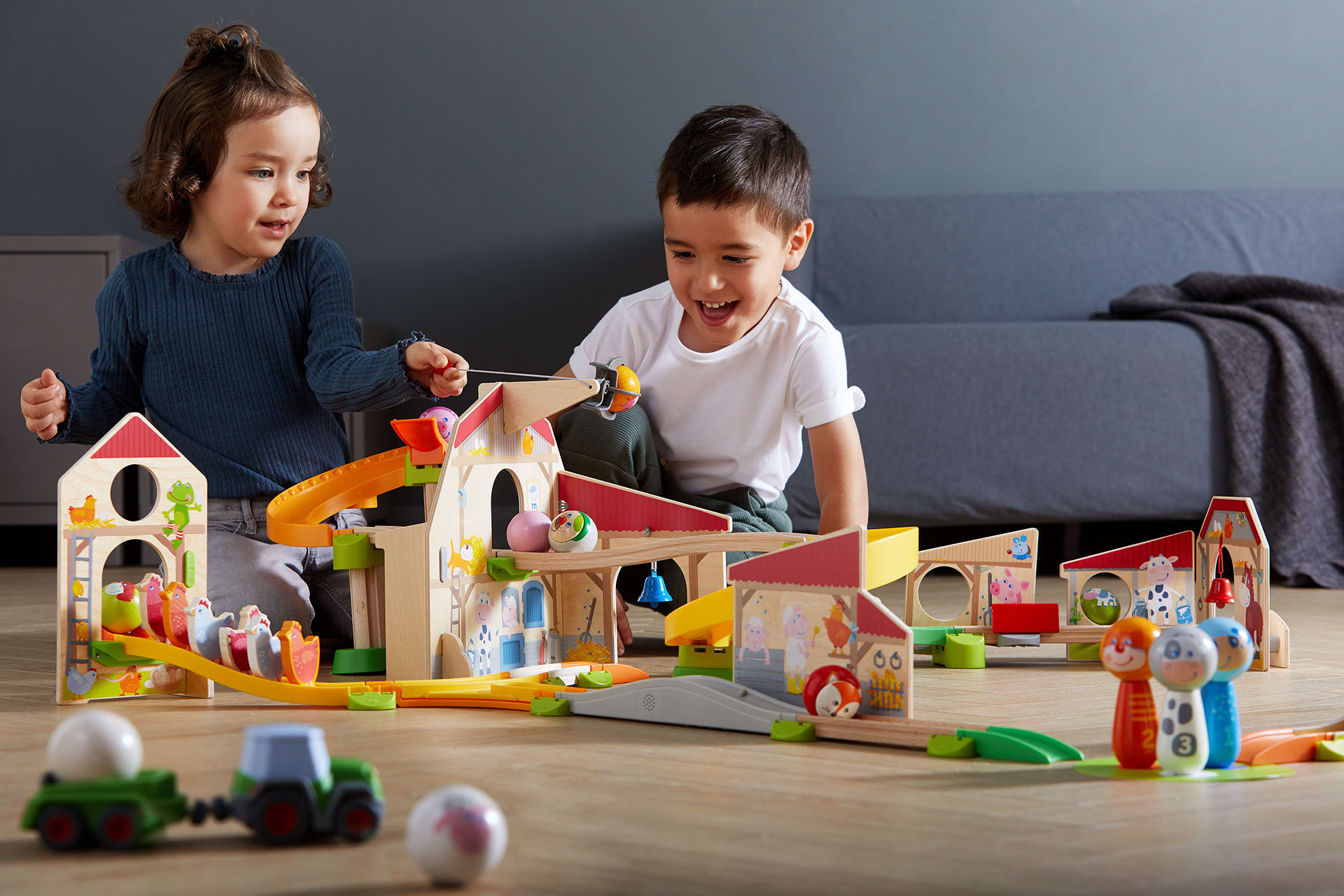 Bauen | Kinder sitzen auf dem Boden und spielen mit Holzbausteinen 