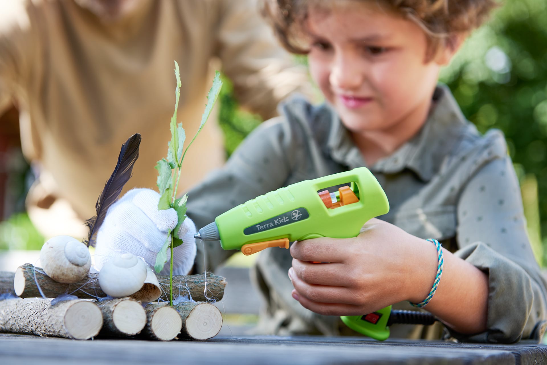  Insektenhotel mit Kindern bauen | Junge hat grüne Heißklebepistole in der Hand