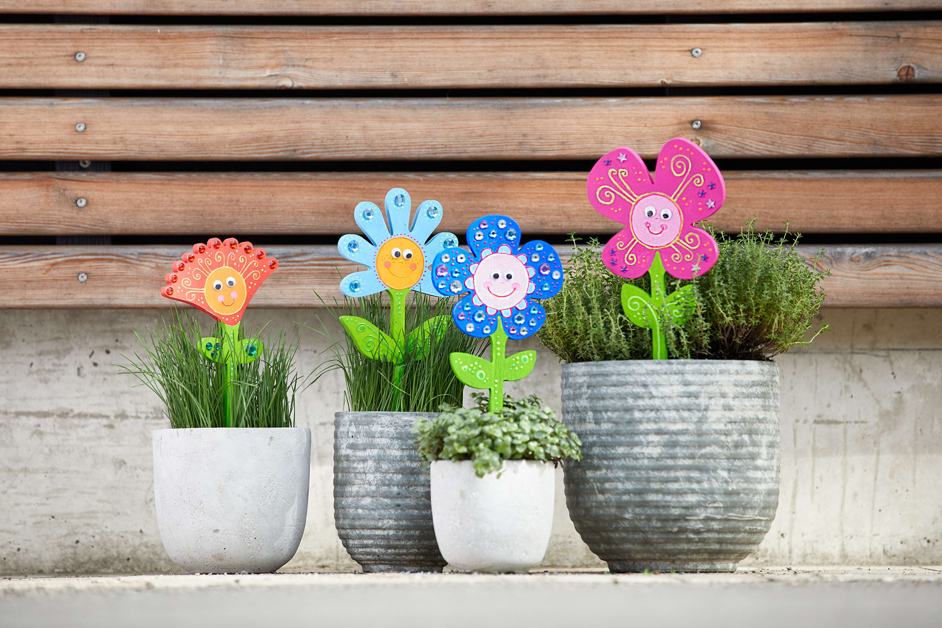  Blumen basteln mit Kindern | Bunt bemalte Blumen aus Holz stecken in Kräutertöpfen