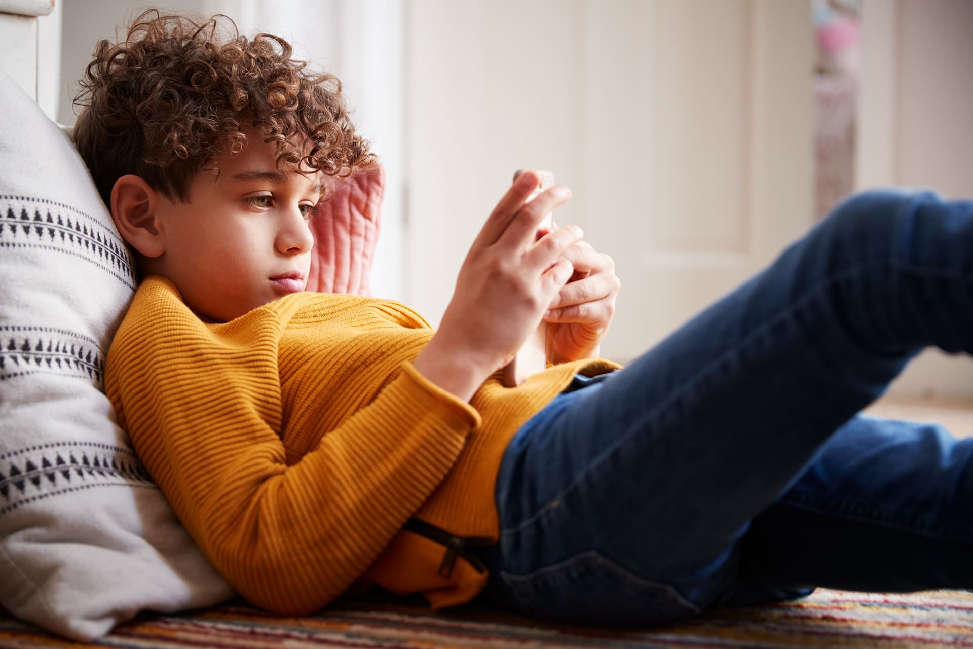 Digitale Medien - Fluch oder Segen | Junge liegt auf dem Boden mit Handy