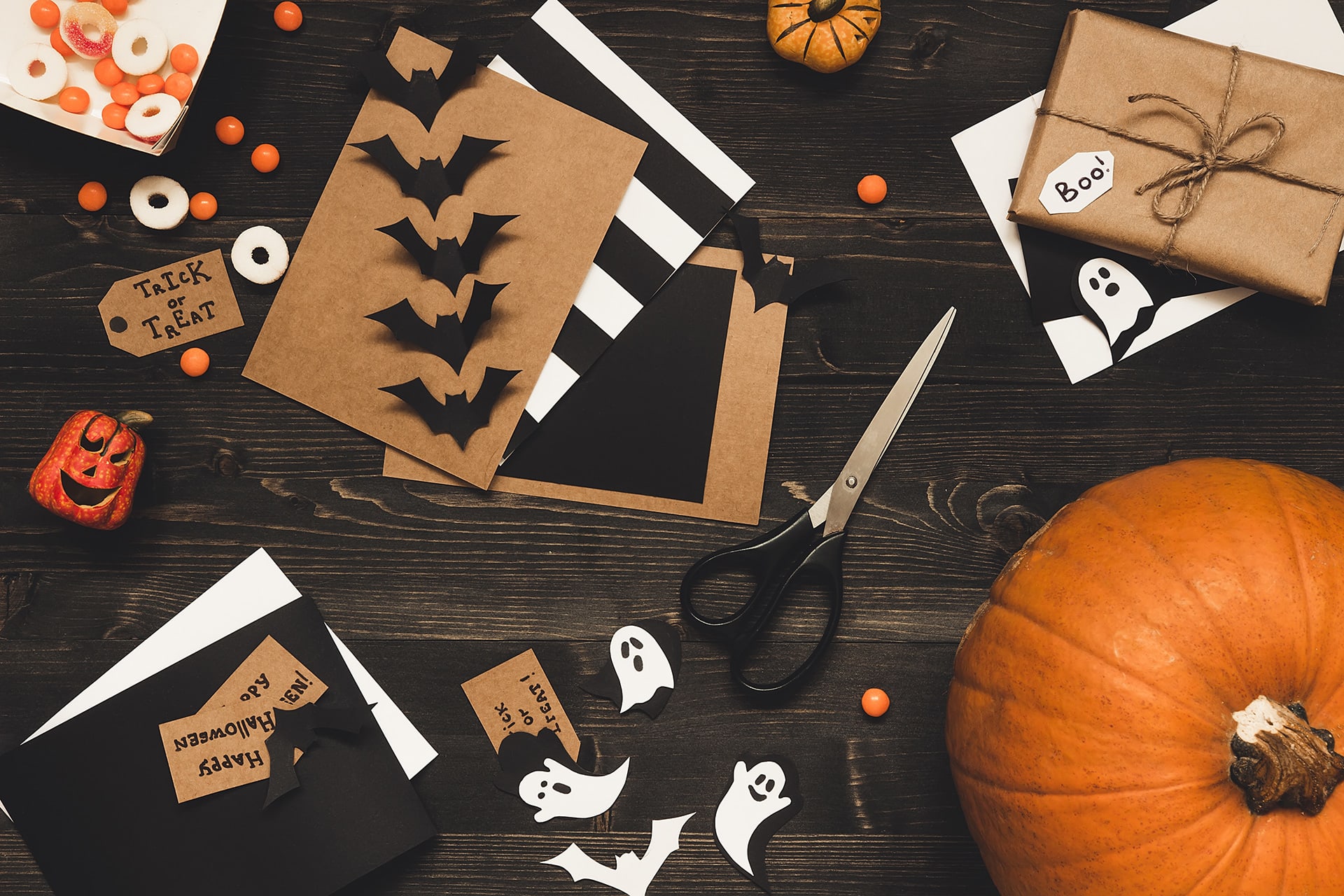 Halloween mit Kindern | Gebastelte Einladungskarten mit Schere und Papier auf einem Tisch