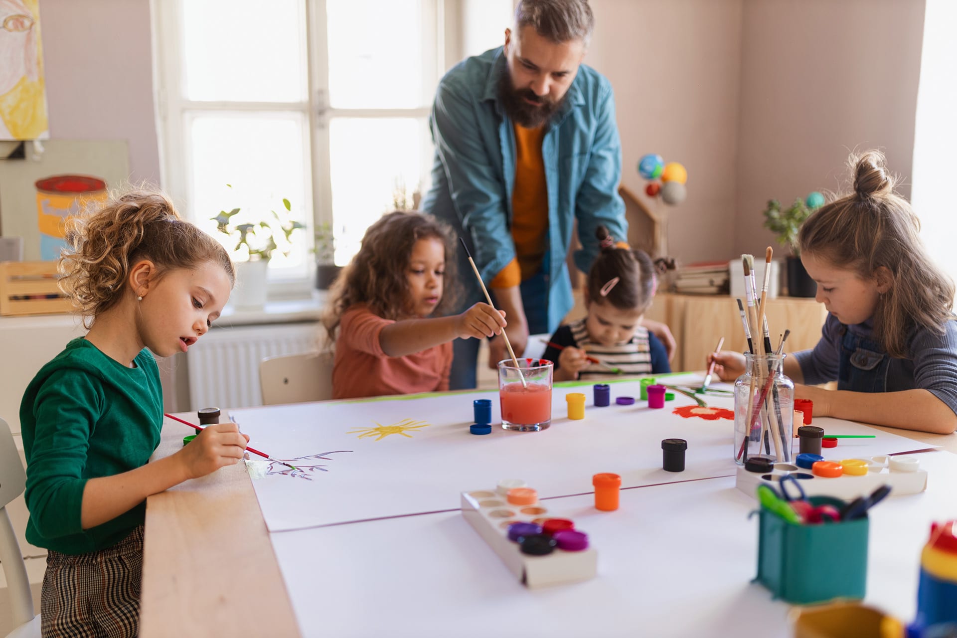 Männliche Erzieher | Erzieher malt mit Kindern mit Pinsel und Farbe
