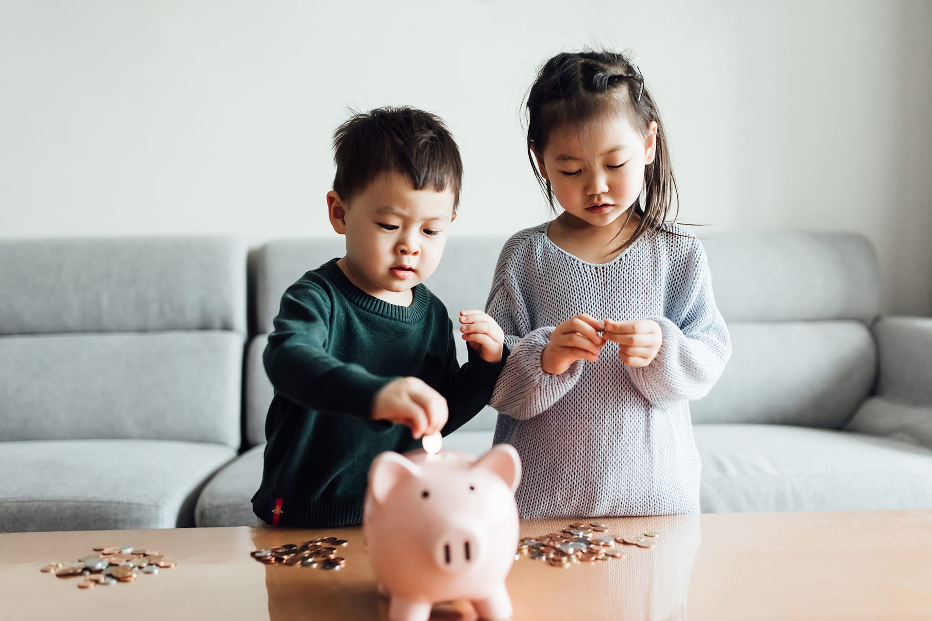 Wie viel Taschengeld | Kinder stehen am Tisch und Sparschwein auf dem Tisch.